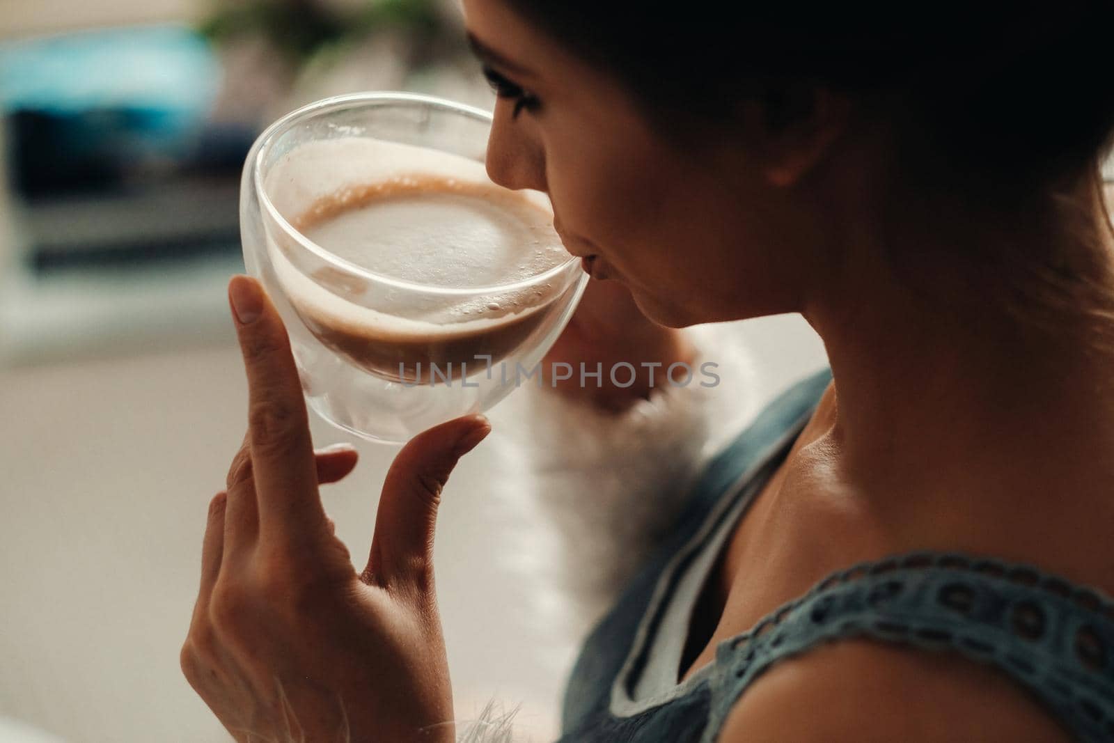 a relaxed girl at home drinks coffee and watches a movie.Domestic calm.The girl is sitting comfortably on the sofa and drinking coffee by Lobachad