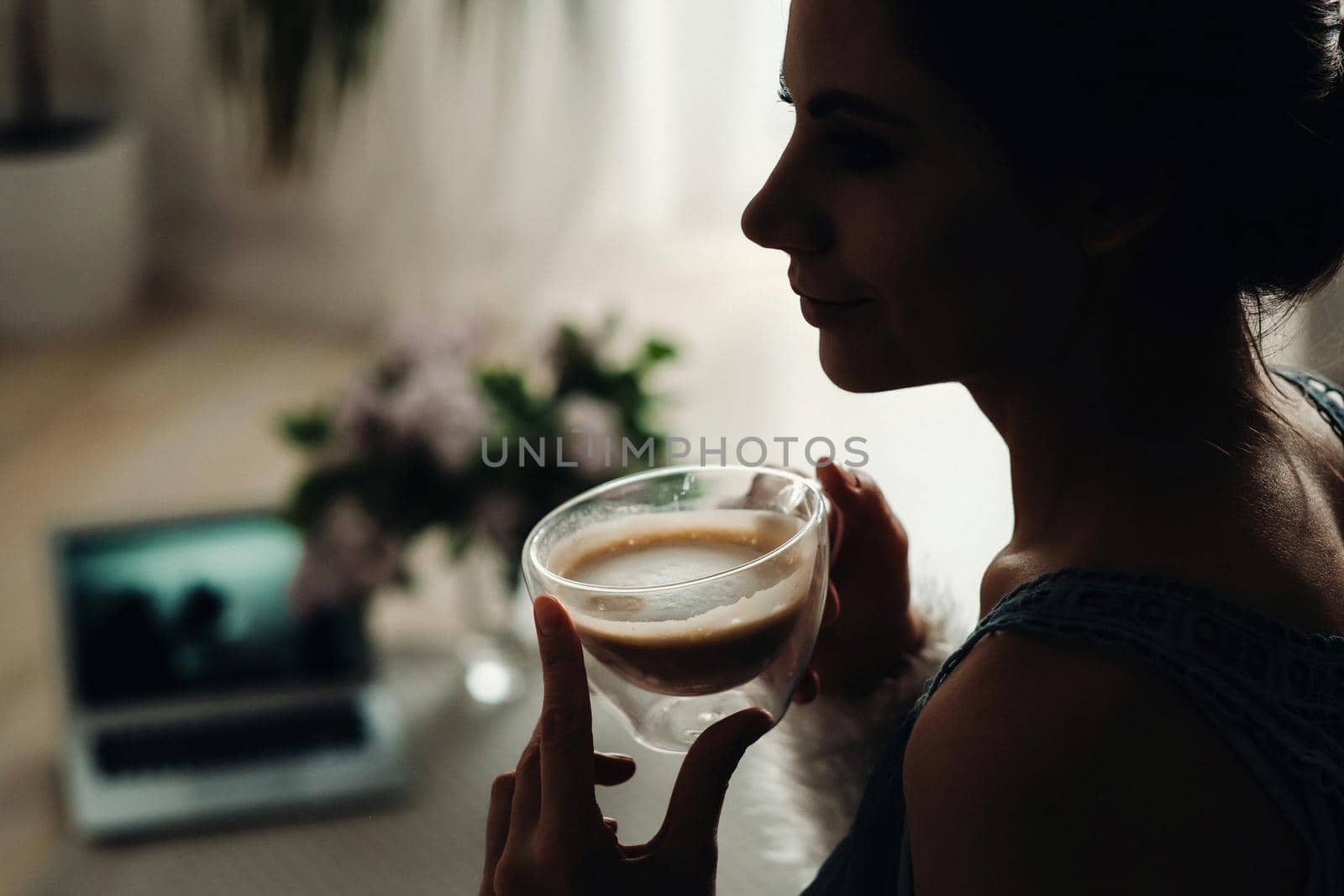 a relaxed girl at home drinks coffee and watches a movie.Domestic calm.The girl is sitting comfortably on the sofa and drinking coffee.