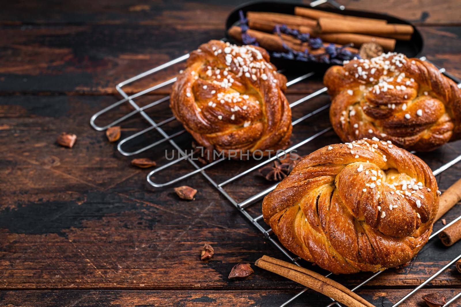 Homemade fresh baked Cinnamon buns or rolls, Swedish Kanelbullar. Dark wooden background. Top view. Copy space.