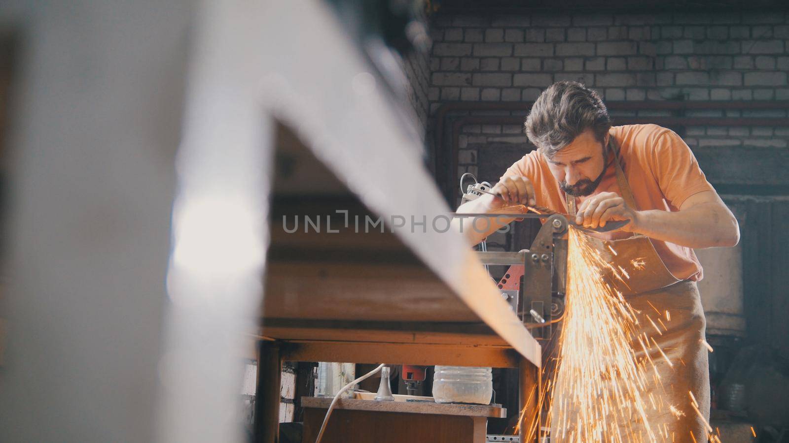 Grinding metal tools with sparkles - forge workshop, manufacturing