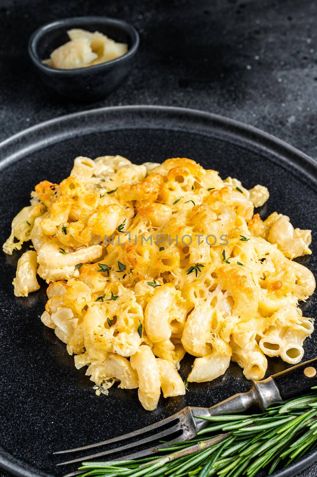 Baked Macaroni Mac and cheese American dish with Cheddar cheese sauce. Black background. Top view.