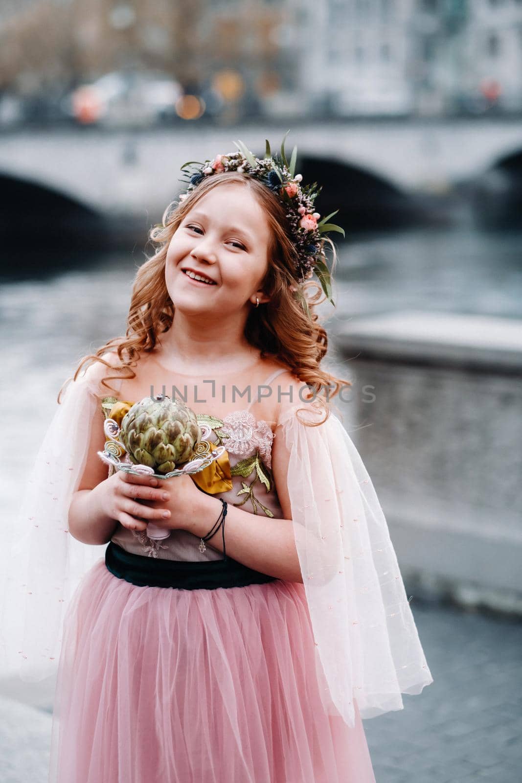 a little girl in a pink Princess dress with a bouquet in her hands walks through the old city of Zurich.Portrait of a girl in a pink dress on a city street in Switzerland.