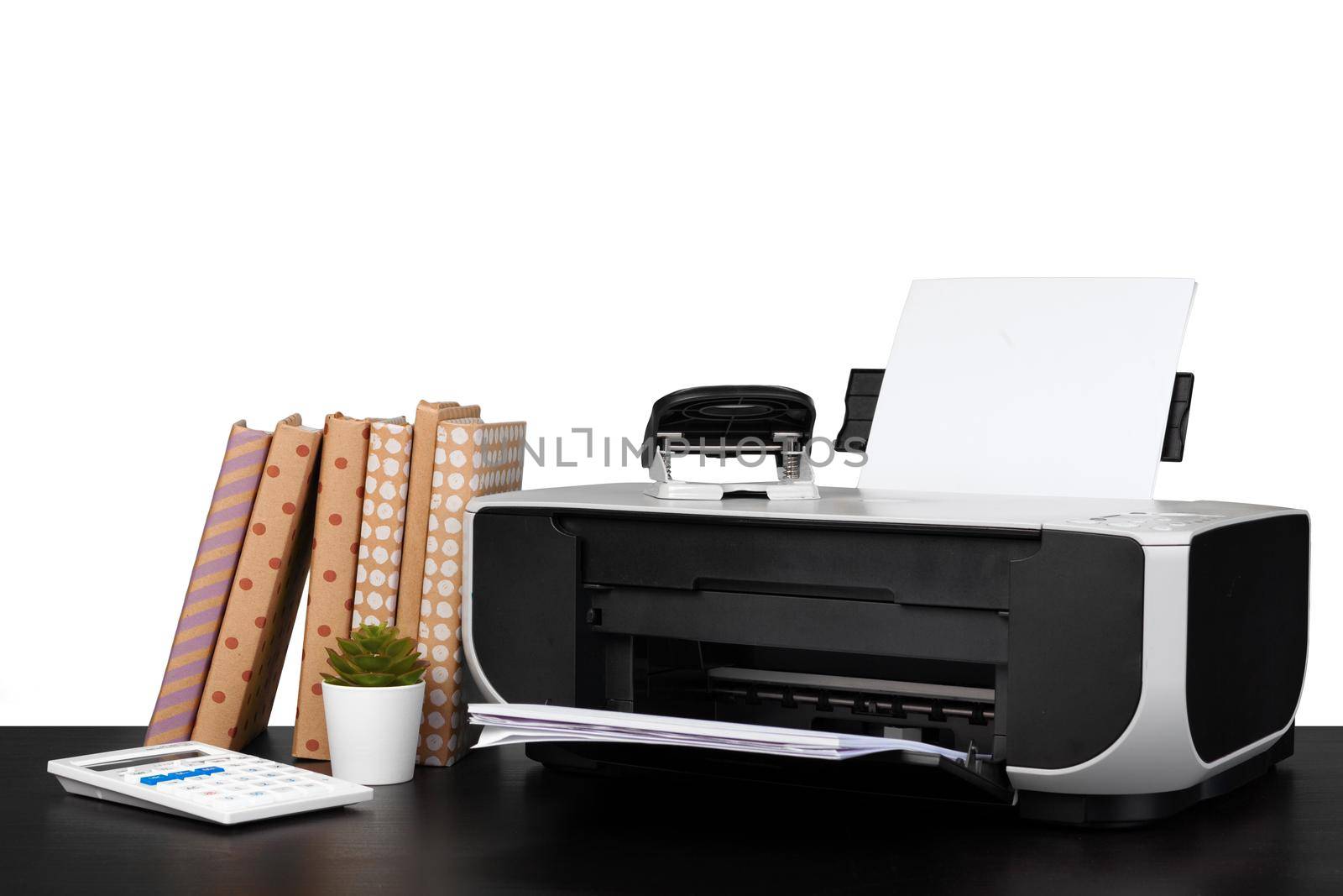 Printer and stack of books on black table against white background, close up