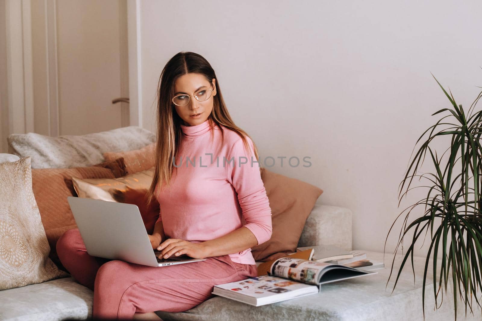 a girl in the morning in pajamas and glasses at home works on a laptop, a girl self-isolates at home and rests on the couch and watches a laptop.Household chores by Lobachad