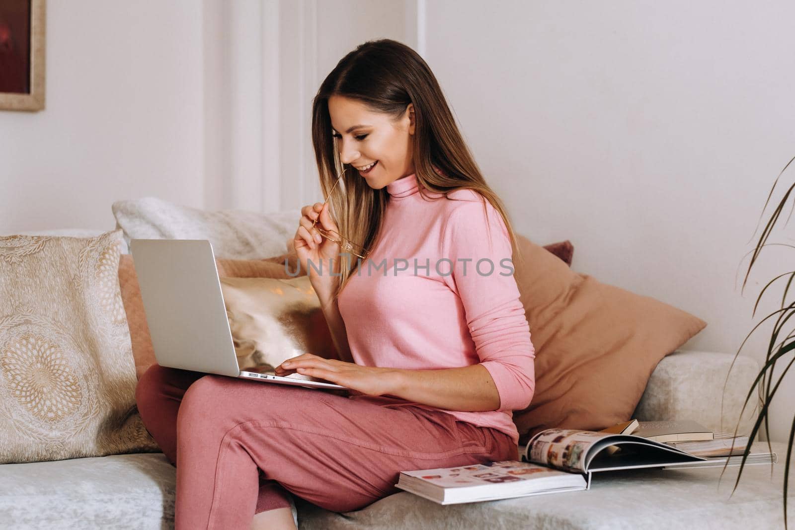 a girl in the morning in pajamas and glasses at home works on a laptop, a girl self-isolates at home and rests on the couch and watches a laptop.Household chores.