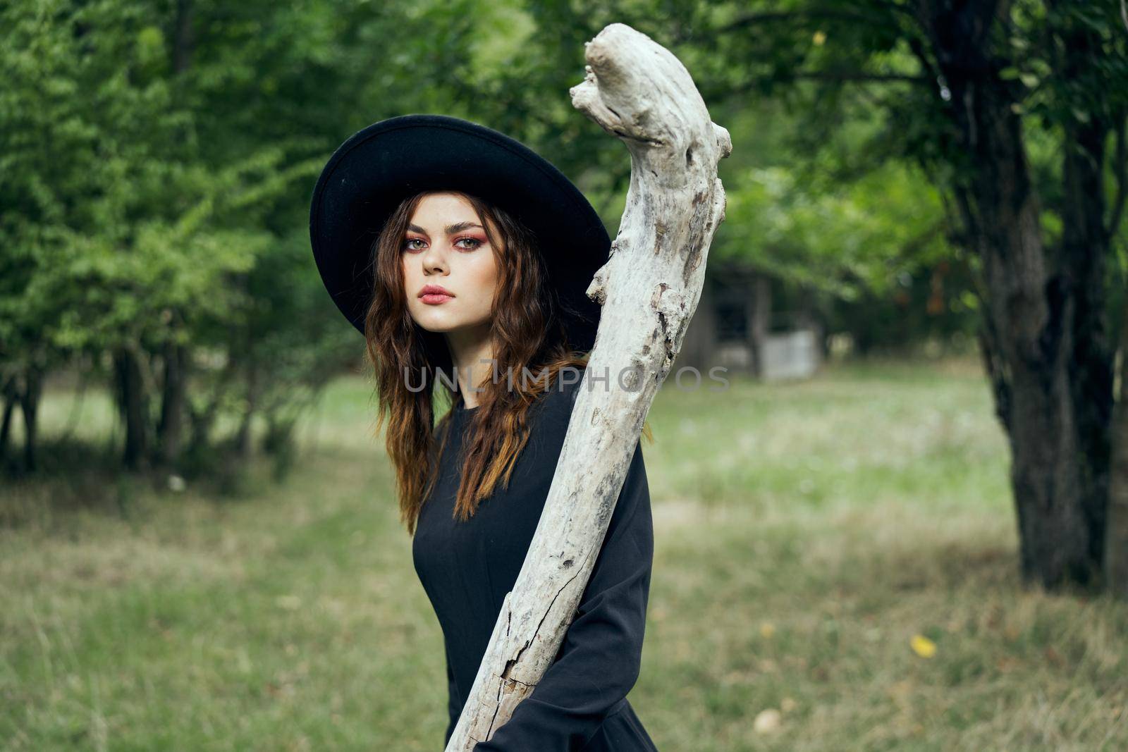 woman in black witch costume in forest nature posing. High quality photo