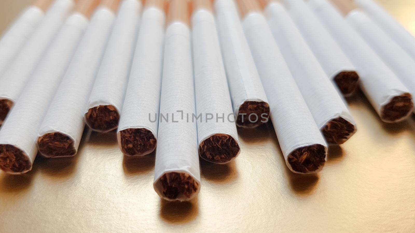 Image of several commercial cigarettes. pile of cigarettes on a gold background or concept of anti-smoking campaign, tobacco.