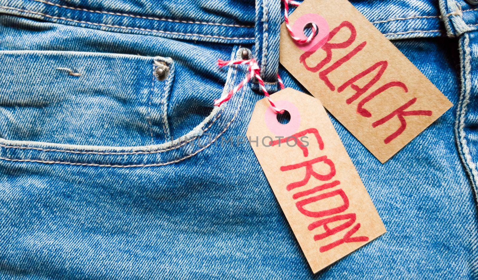 Stylish jeans with a black friday flag. Black friday and cyber monday sale discount concept tag with blue jeans. Black friday written on grunge jeans texture. Background, holiday concept. Black Friday - International day of shopping, promotions, discounts, sales. The sales season is the fourth Thursday of November. Copy space, place for text, flat lay.