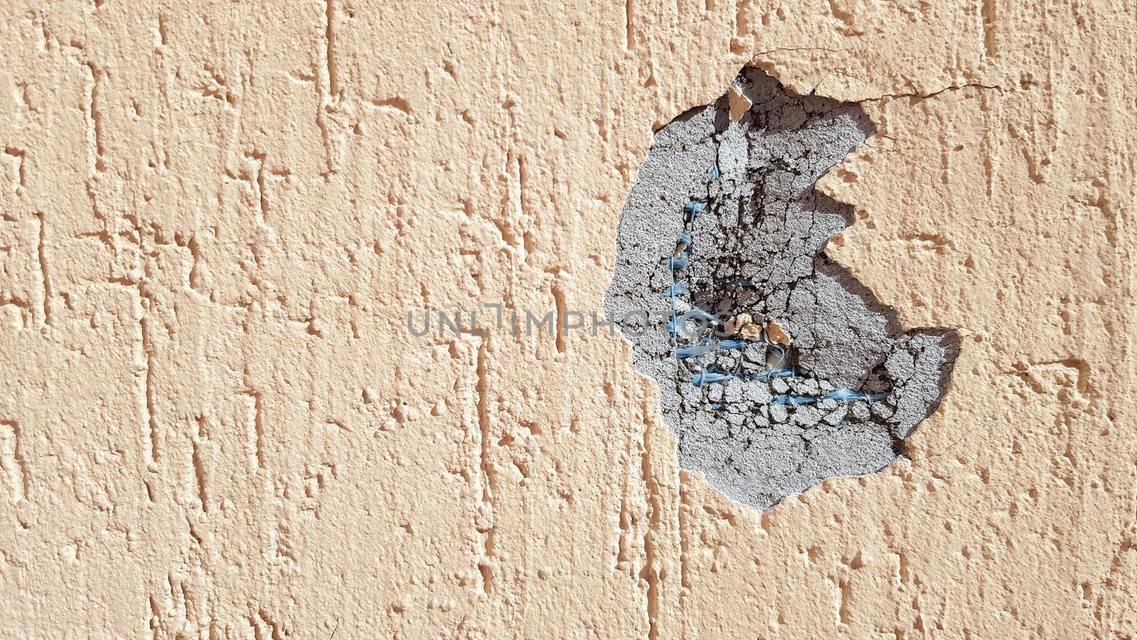 dent on a yellow concrete wall. Hole in the wall with foam insulation. Crack on the yellow wall with decorative putty.