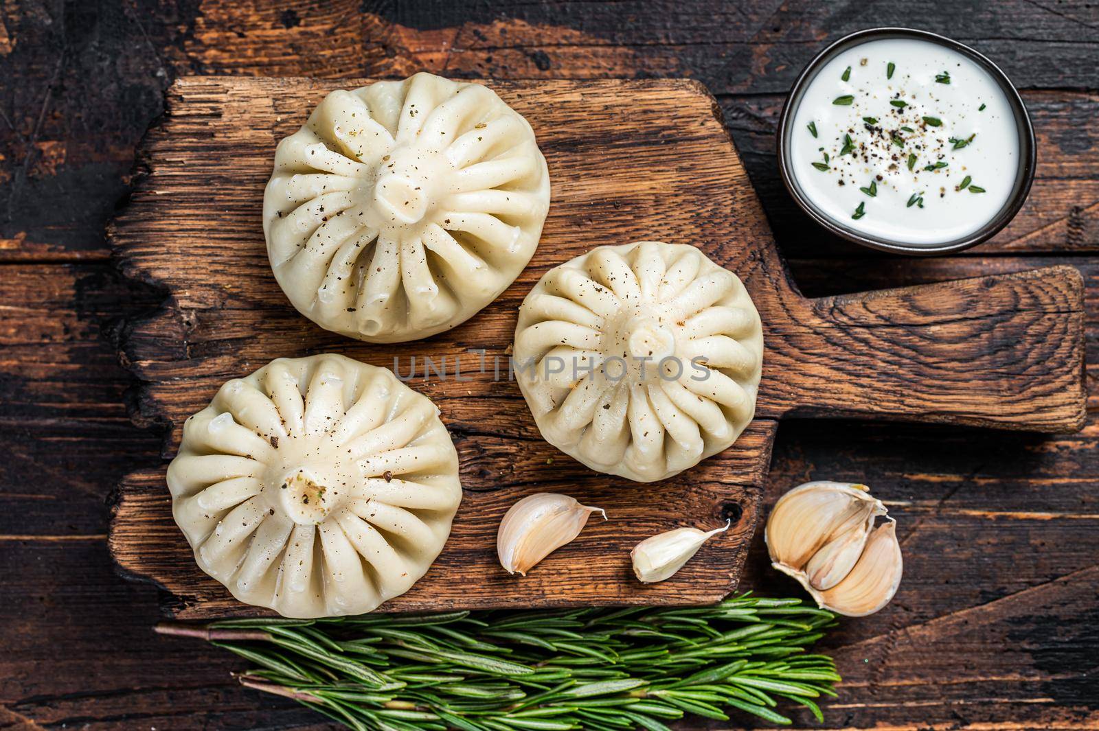 Georgian Khinkali Dumplings with beef and lamb meat on wooden board with herbs. Dark wooden background. Top view by Composter