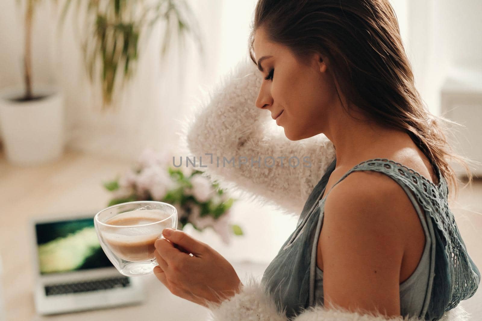 a relaxed girl at home drinks coffee and watches a movie.Domestic calm.The girl is sitting comfortably on the sofa and drinking coffee.