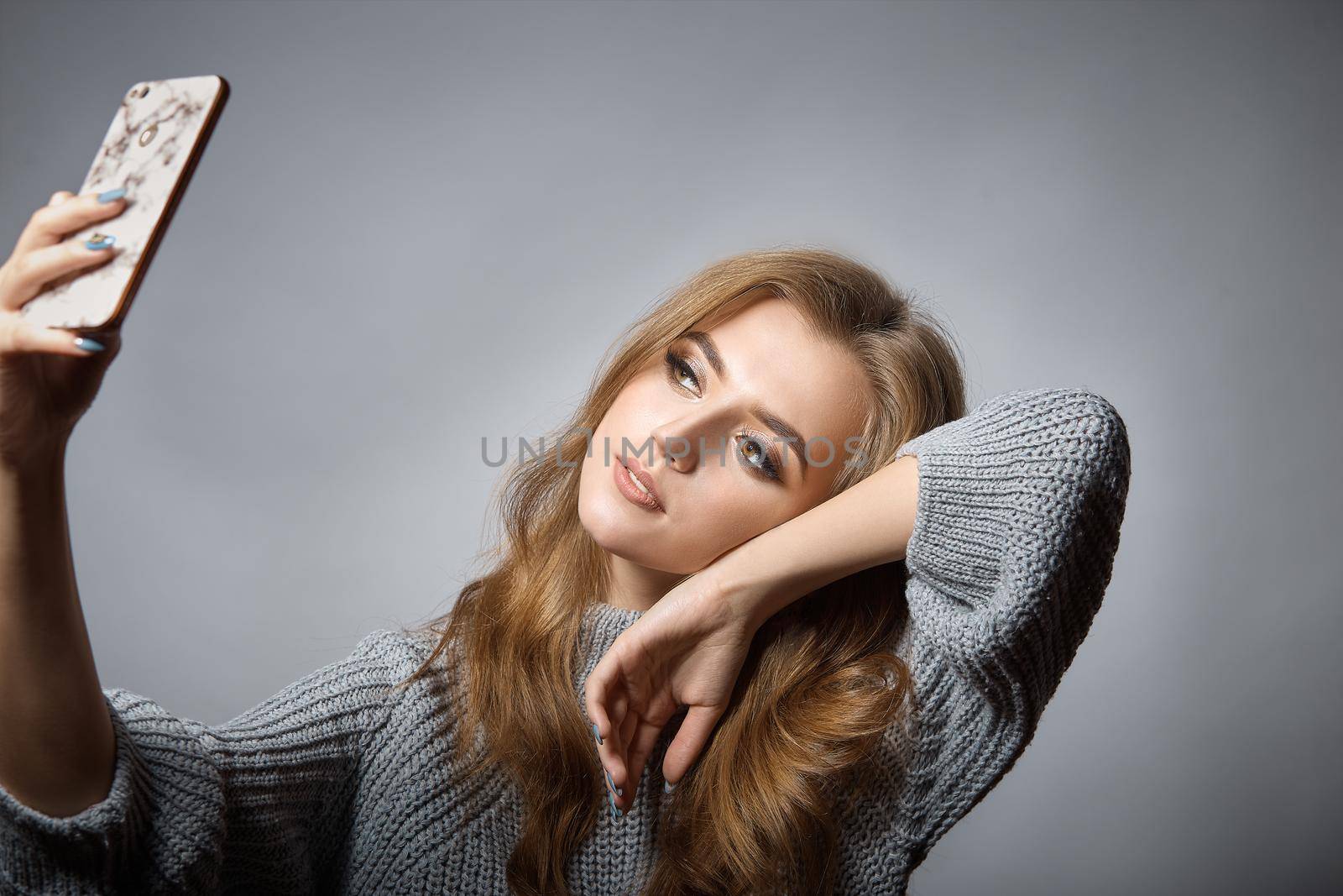 Portrait of a cheerful girl looking at mobile phone isolated over gray background