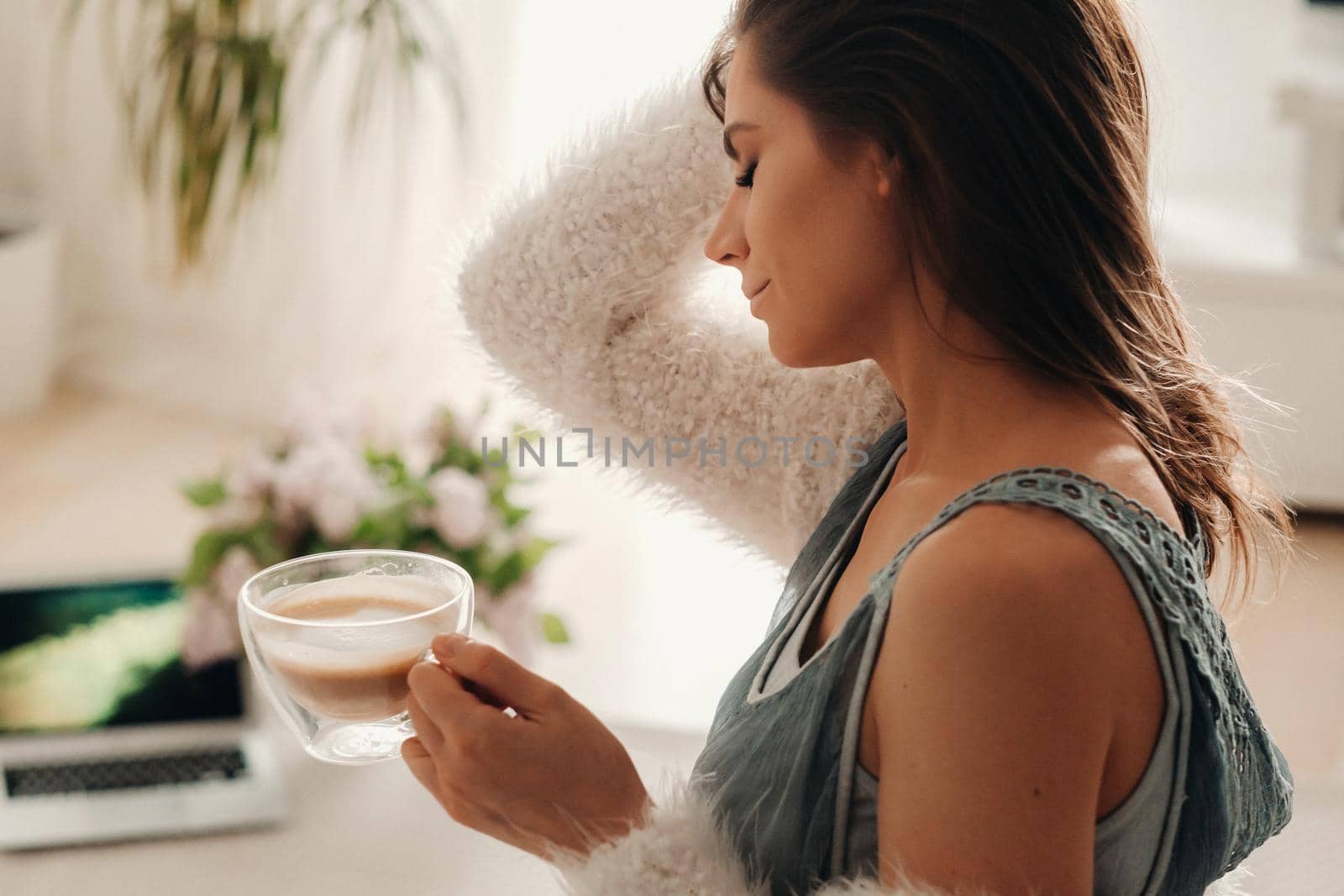 a relaxed girl at home drinks coffee and watches a movie.Domestic calm.The girl is sitting comfortably on the sofa and drinking coffee.