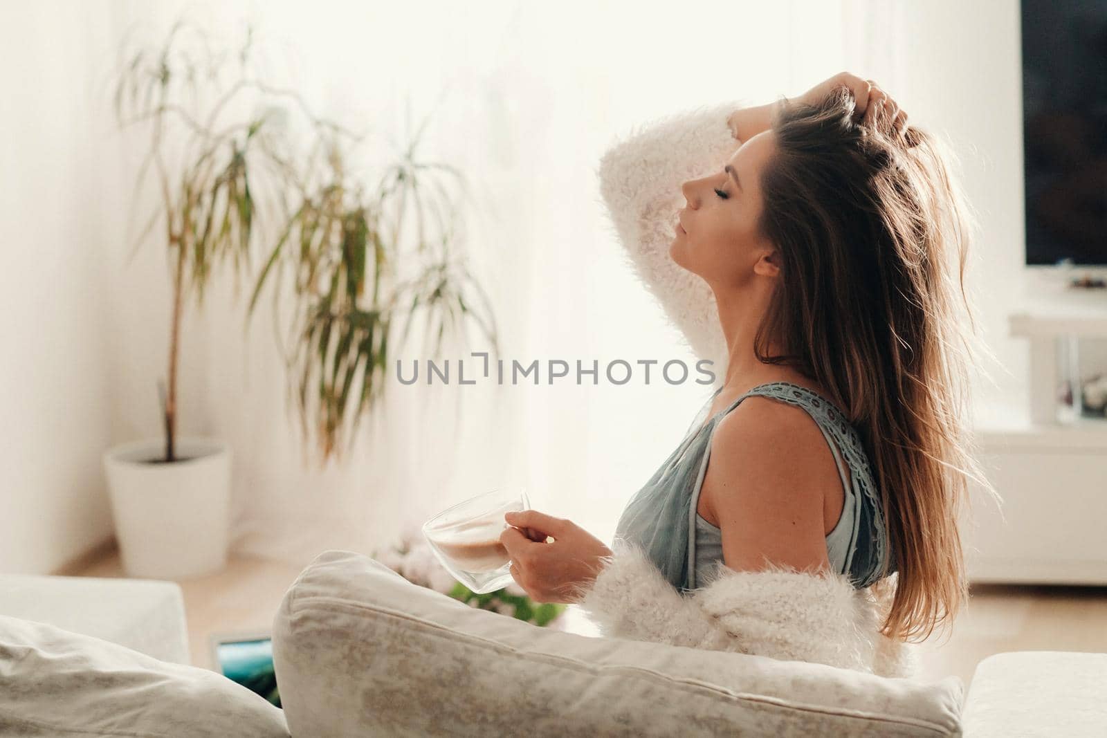 a relaxed girl at home drinks coffee and watches a movie.Domestic calm.The girl is sitting comfortably on the sofa and drinking coffee.