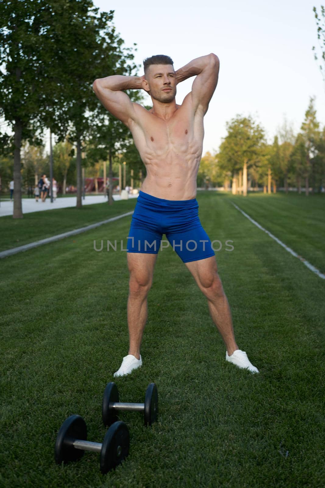 Muscled man in the park training with dumbbells by Vichizh