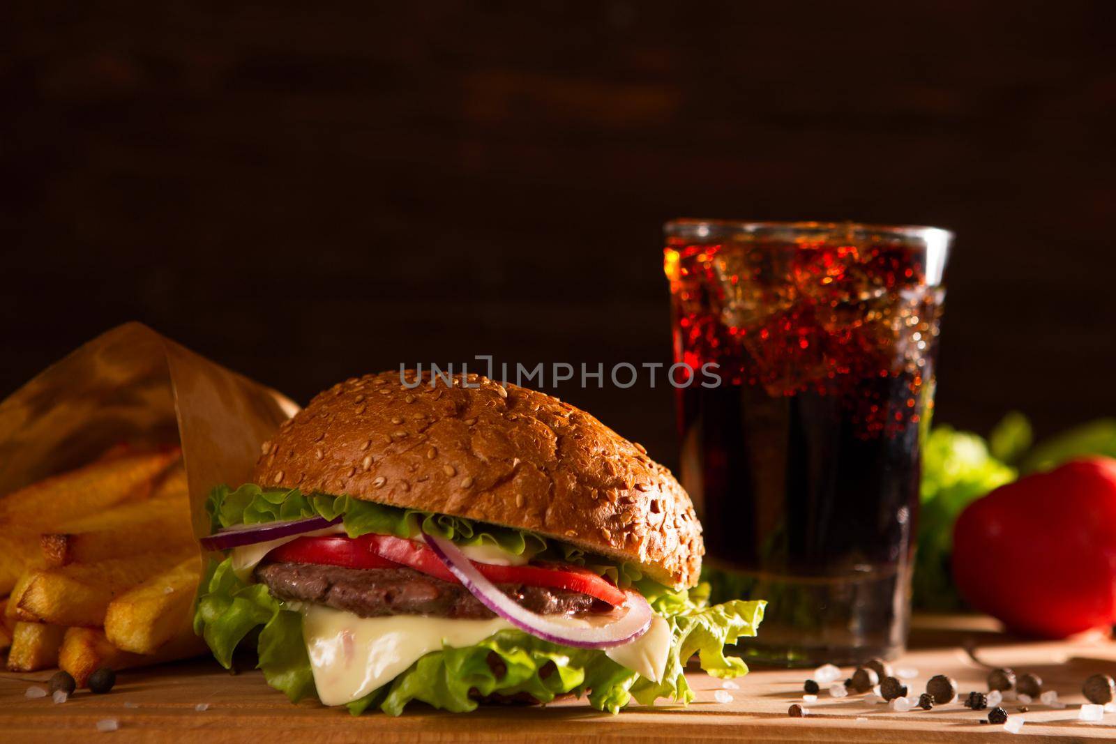 american snack with big burger and glass cola on wooden table.