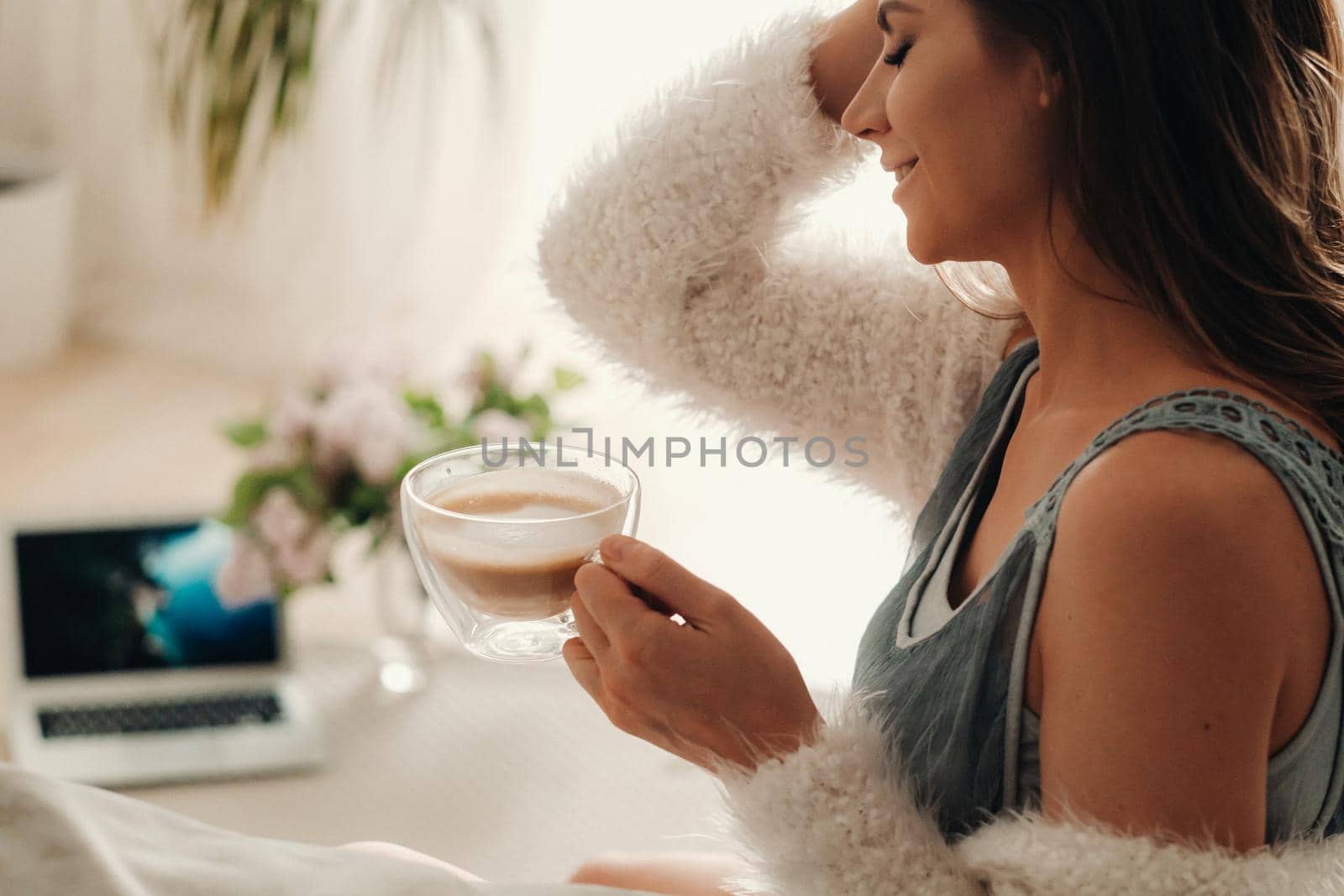 a relaxed girl at home drinks coffee and watches a movie.Domestic calm.The girl is sitting comfortably on the sofa and drinking coffee.