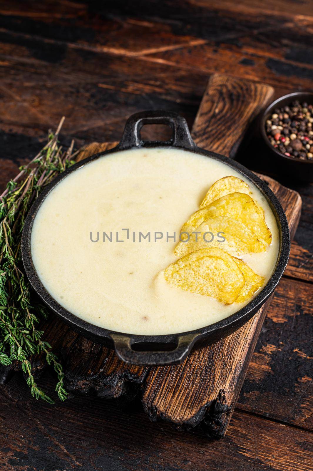 Potato cream soup with potato chips in pan on wooden board. Dark wooden background. Top view by Composter