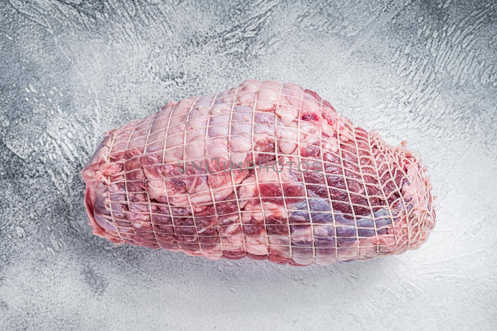 Boneless Leg of Lamb meat on butcher table. White background. Top view.