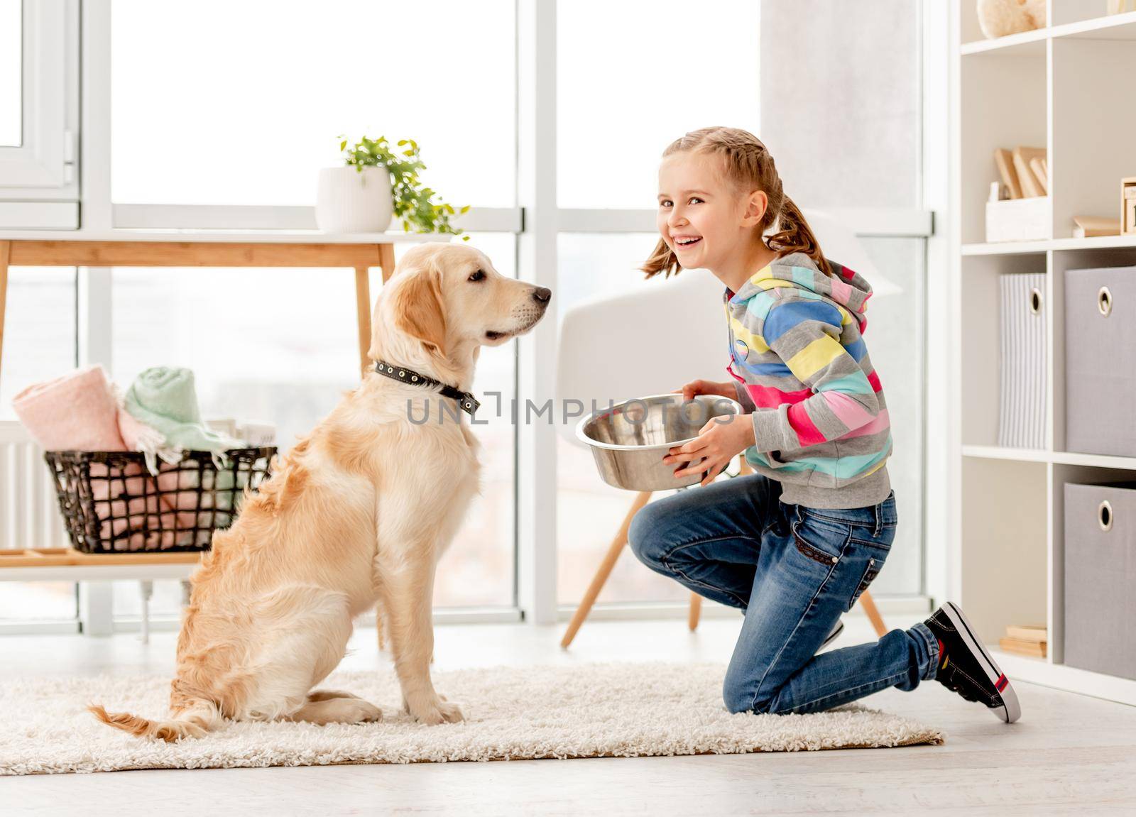 Smiling girl with bowl for adorable dog in living room