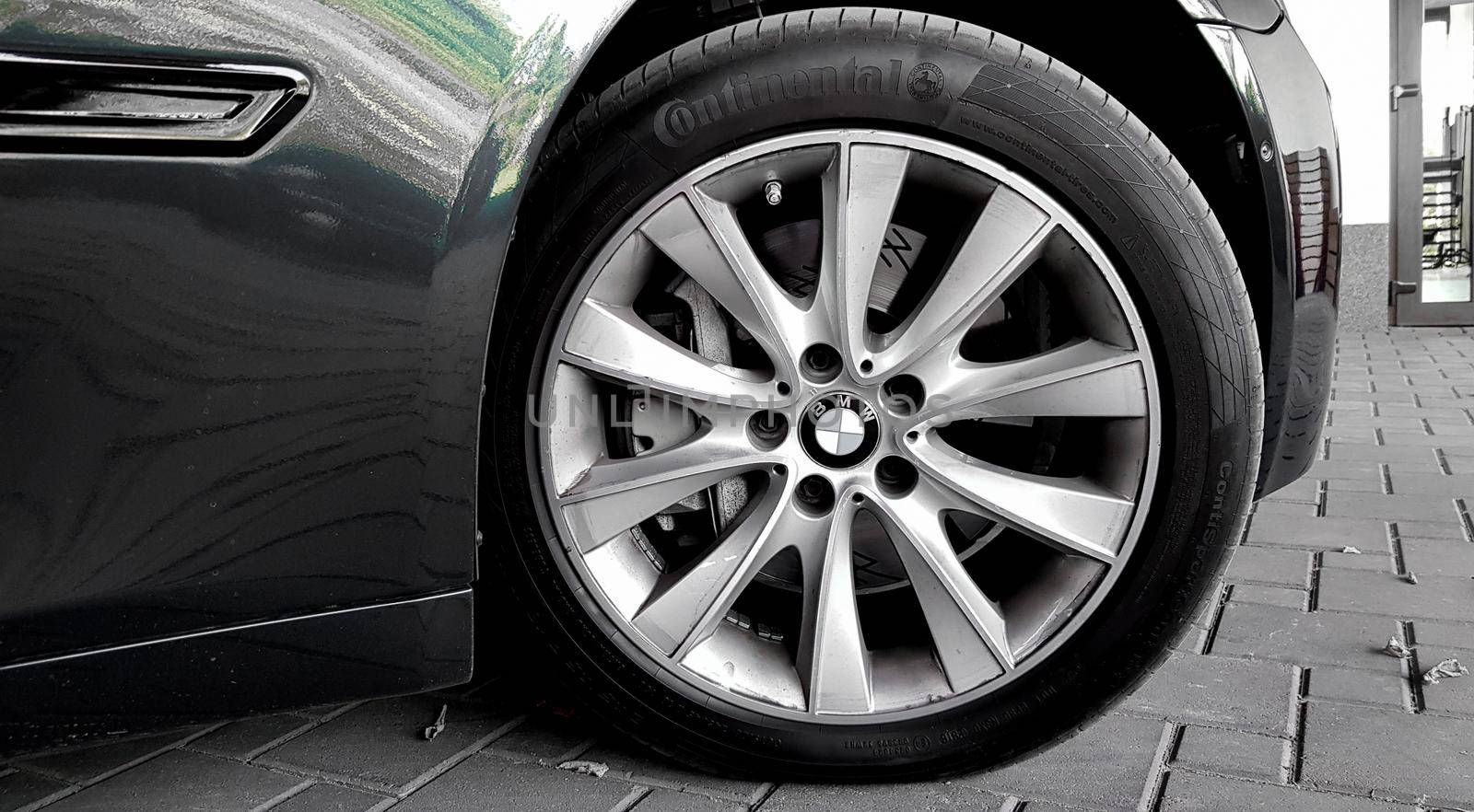 Ukraine, Kiev - September 12, 2019: A new luxury BMW VIP sedan in black and gray is parked in front of the garage door of the house.