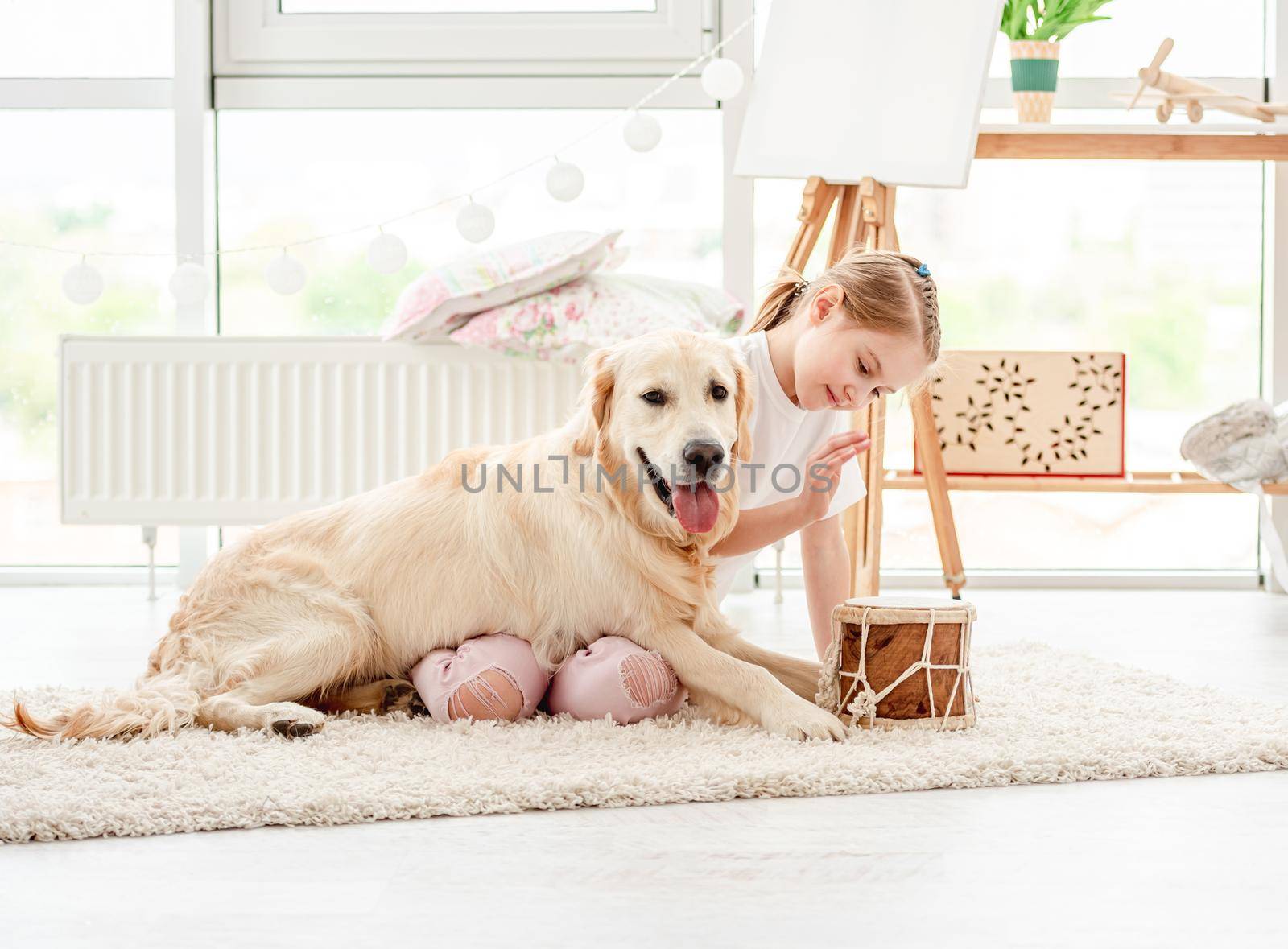 Beautiful little girl playing music with lovely dog indoors