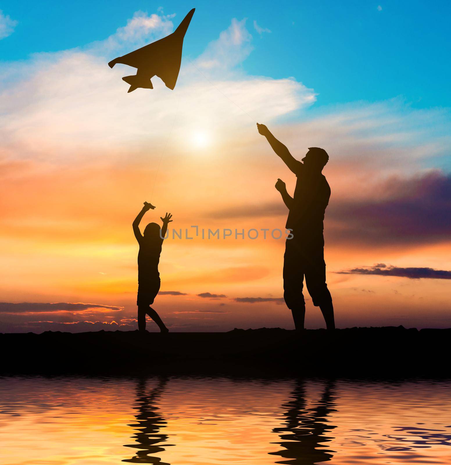 Dad and daughter flying a kite on the beach. silhouette photo