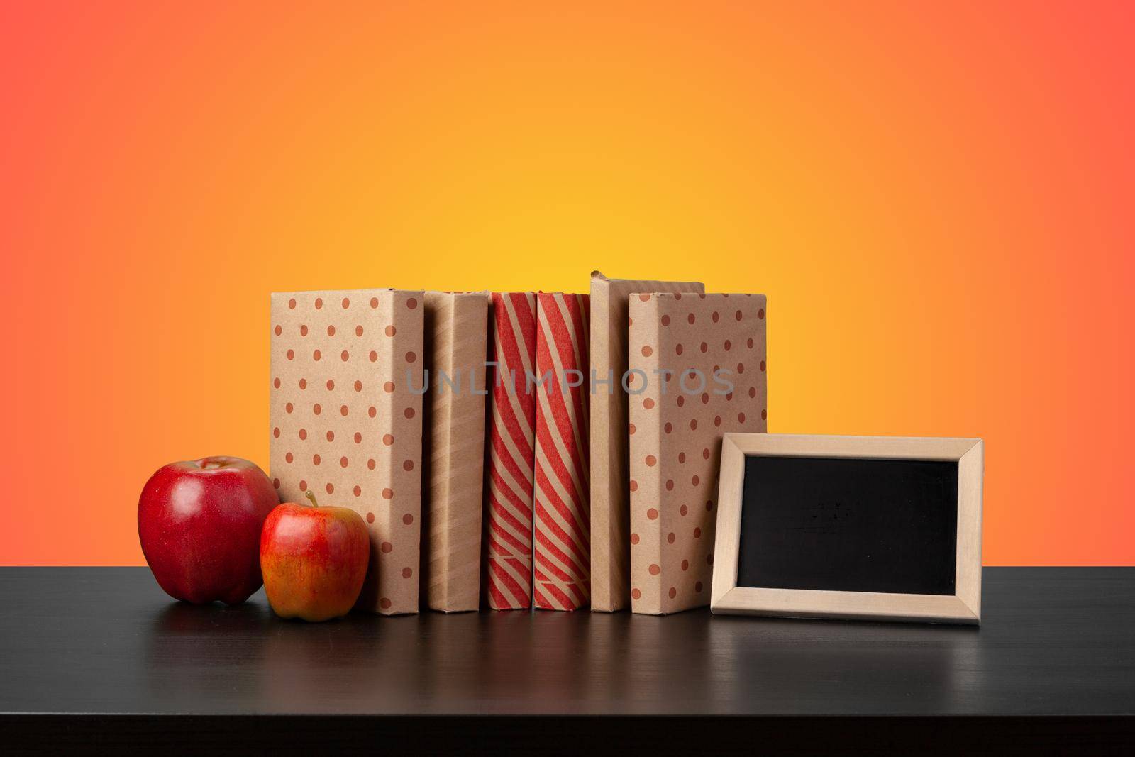 Education concept with stack of books on a table against colored background, front view