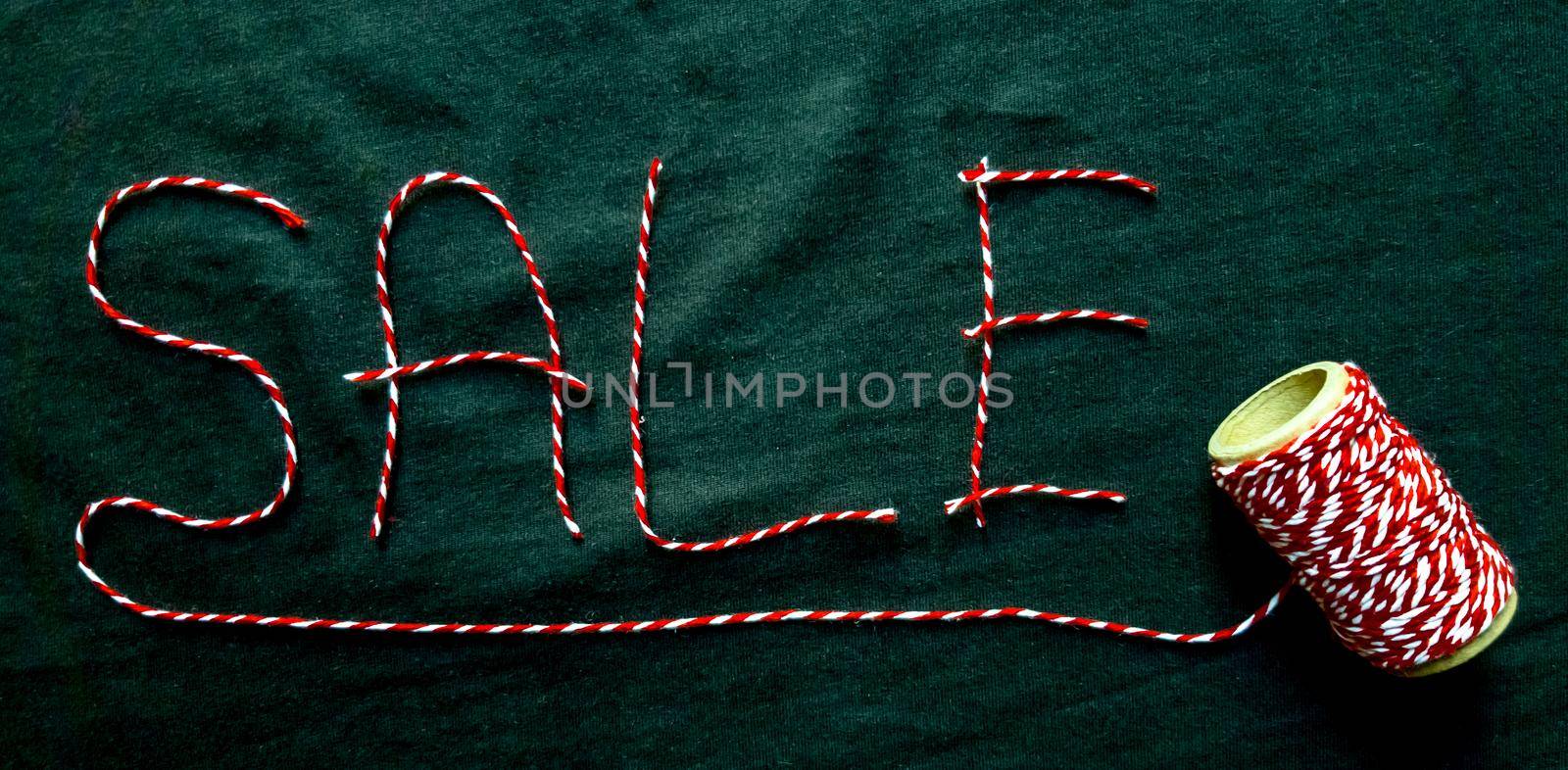 Sale, discount word made of red thread with a spool on a black background. Background, holiday concept. Black Friday - International Day of Shopping, Promotions, Discounts, Sales. Sales season is the fourth Thursday of November. Copy space, place for text, flat lay.