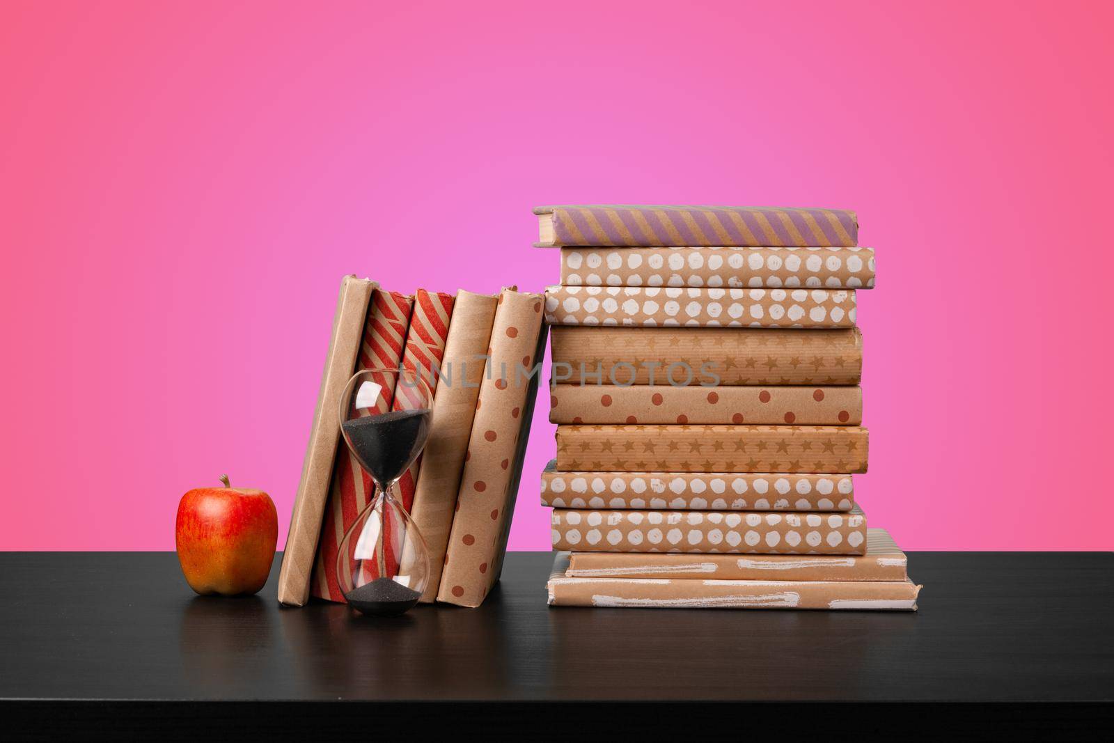 Education concept with stack of books on a table against colored background, front view