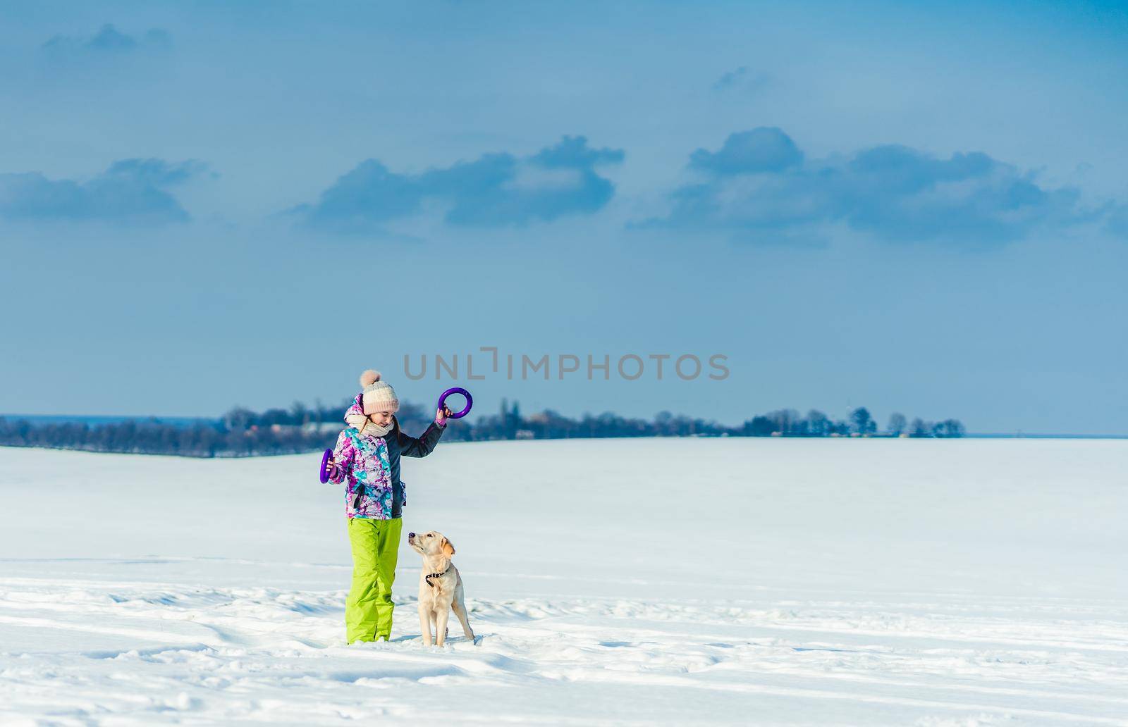 Cute girl playing with adorable dog on snowy field