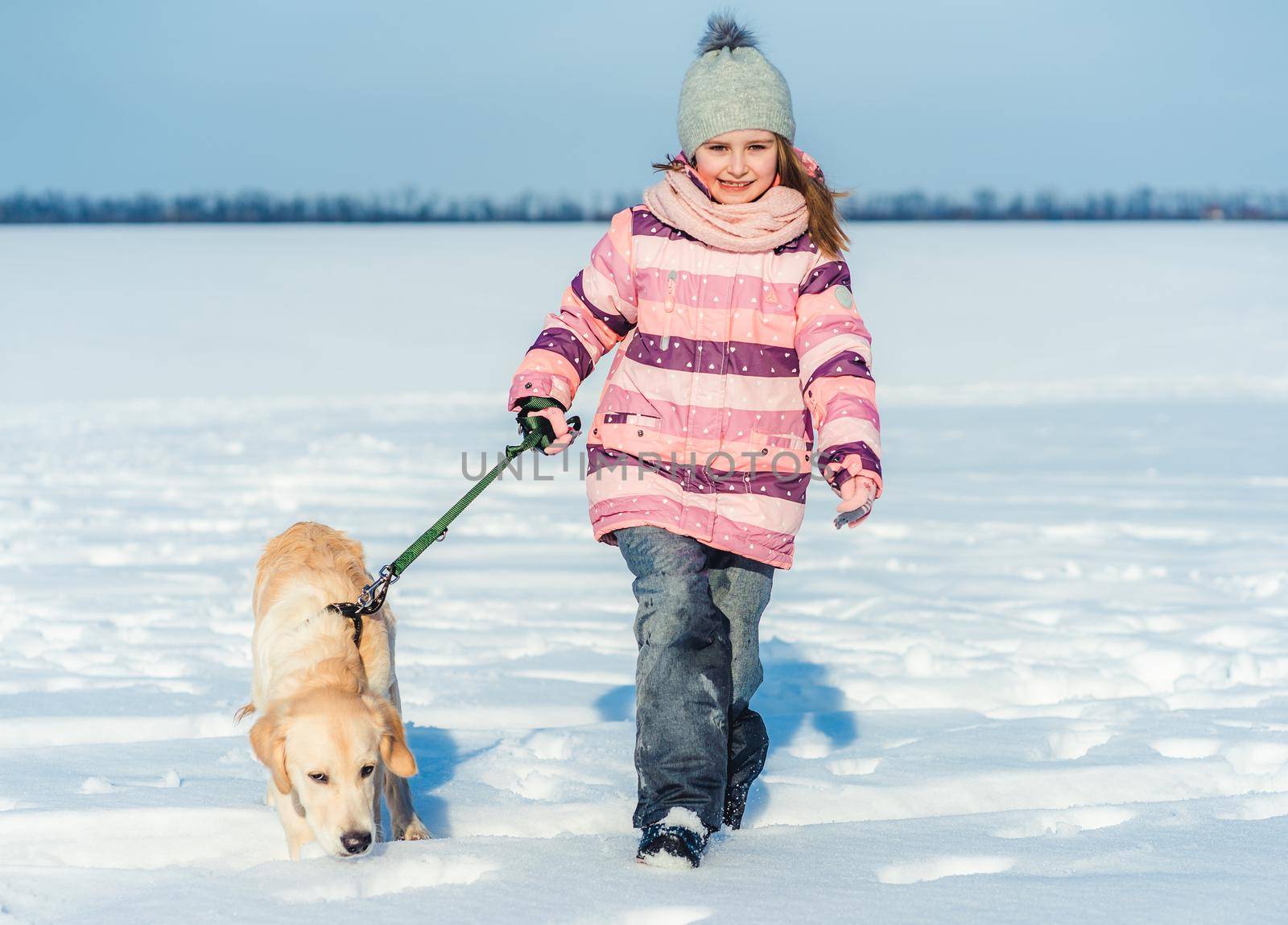 Happy little girl walking with lovely dog on leash in winter