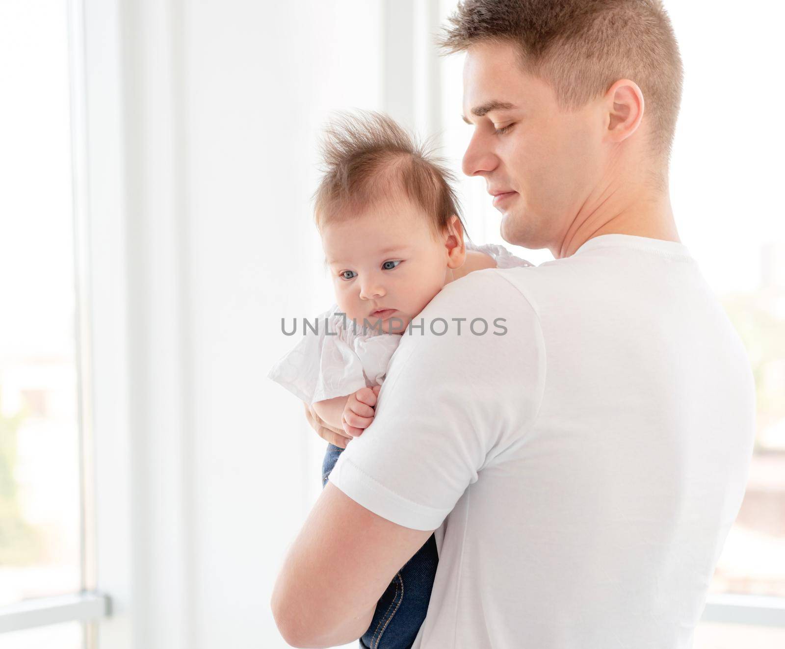 Father embracing infant near window