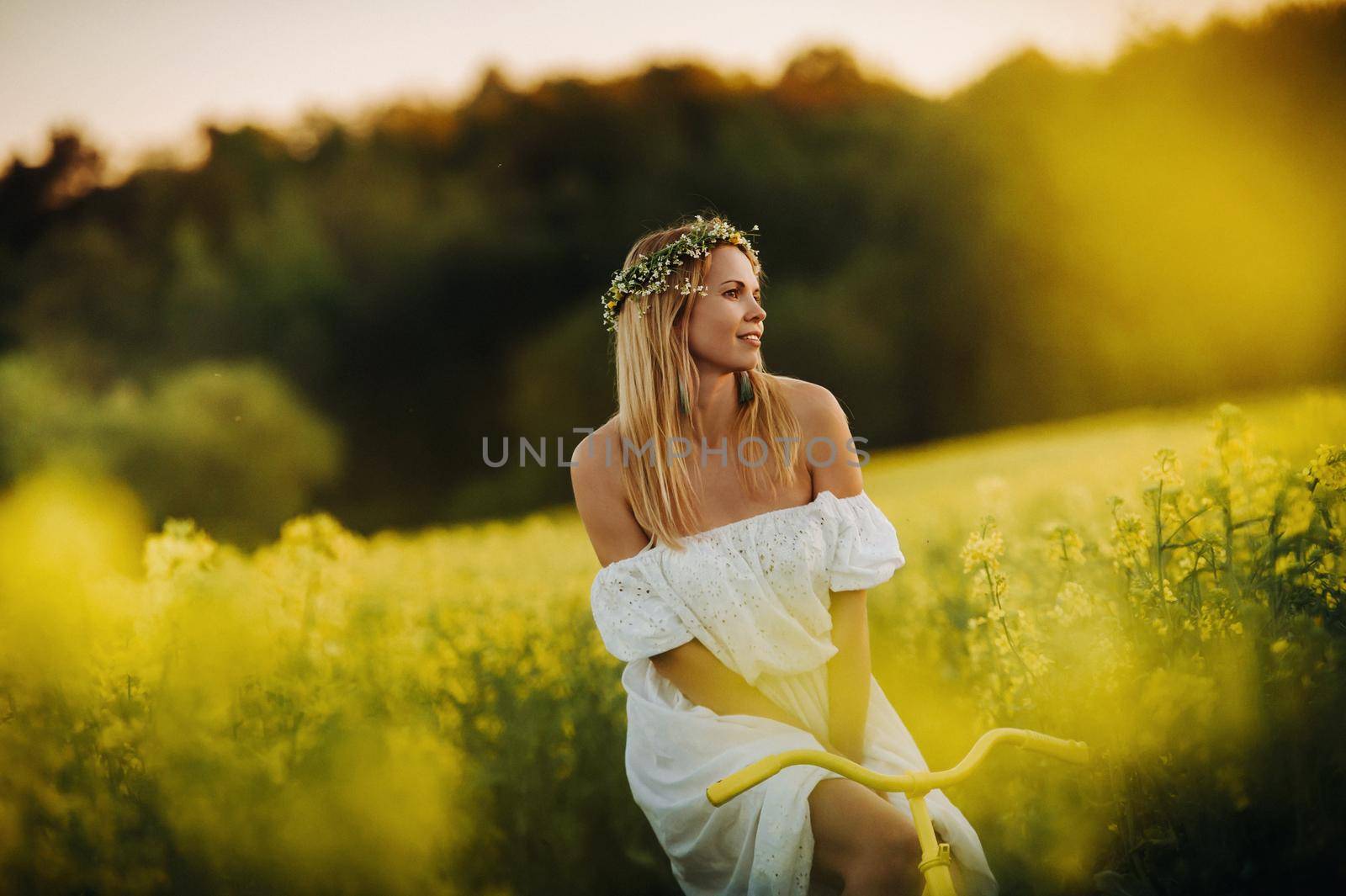 a woman enjoys a bike ride in a field full of bright yellow rapeseed by Lobachad