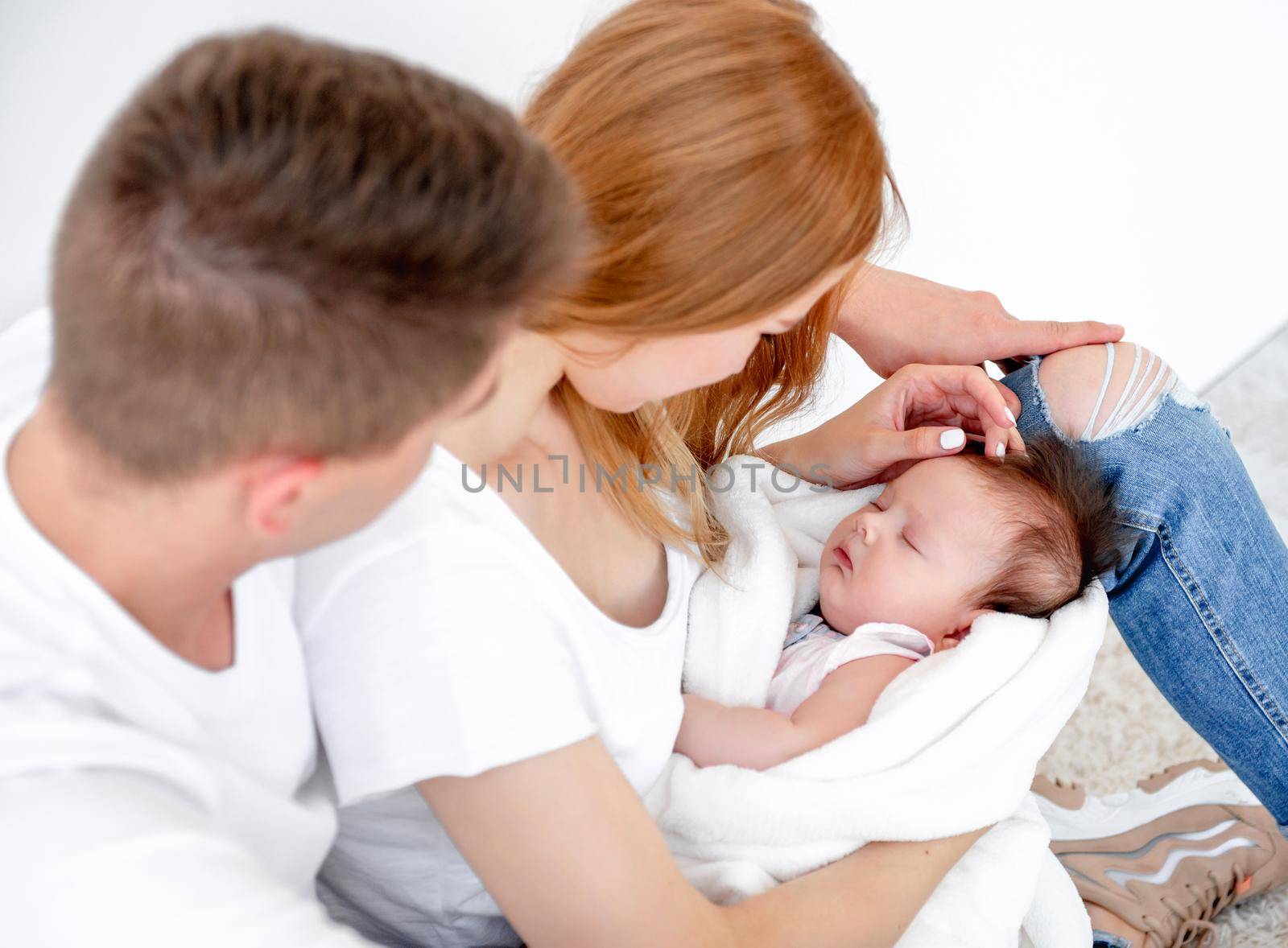 Father, mother and sleeping baby girl at home