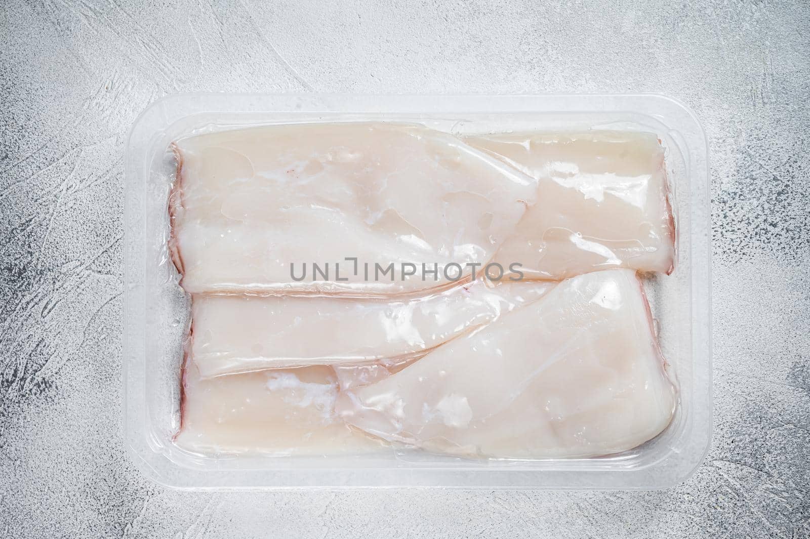 Fresh Raw Squid or Calamari in a vacuum package on a kitchen table. White background. Top view by Composter