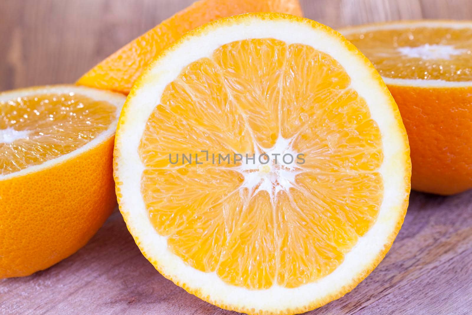 juicy ripe oranges, some of which are cut in half, closeup