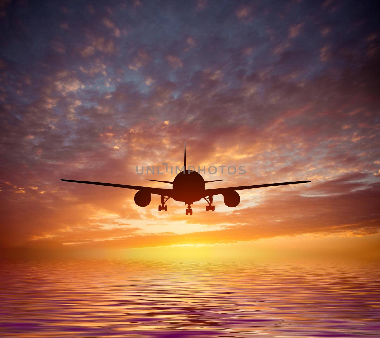 aircraft flies over the ocean on a background of a magnificent sunset