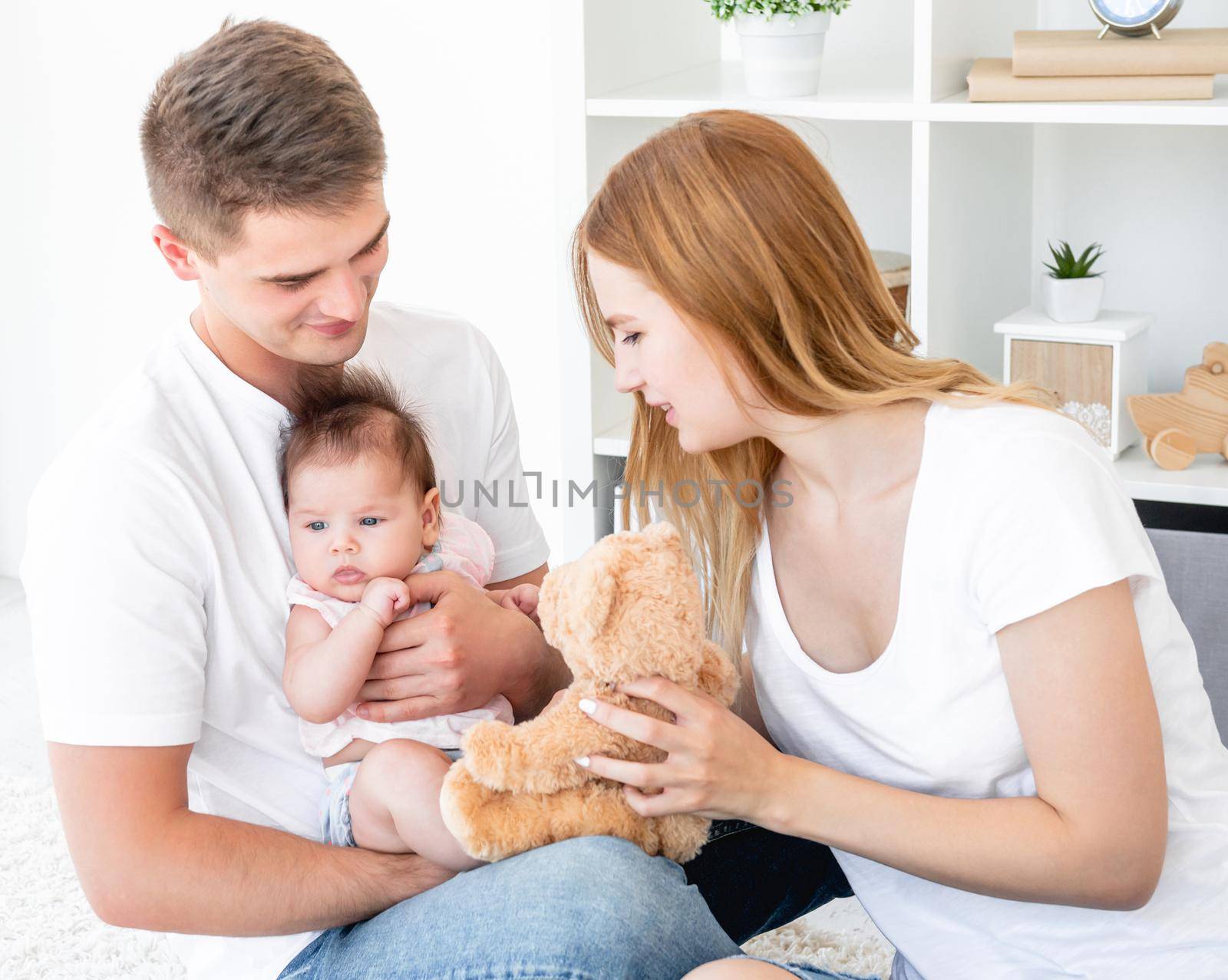 Family play with teddy bear in light room