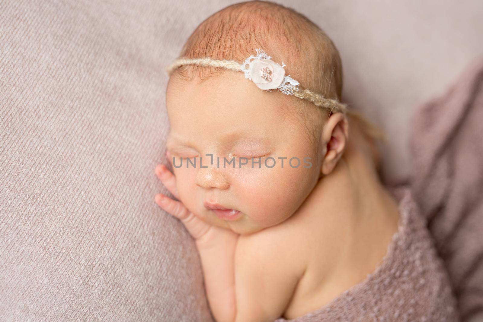 lovely sleeping newborn girl with flower on her headband with hand under her head