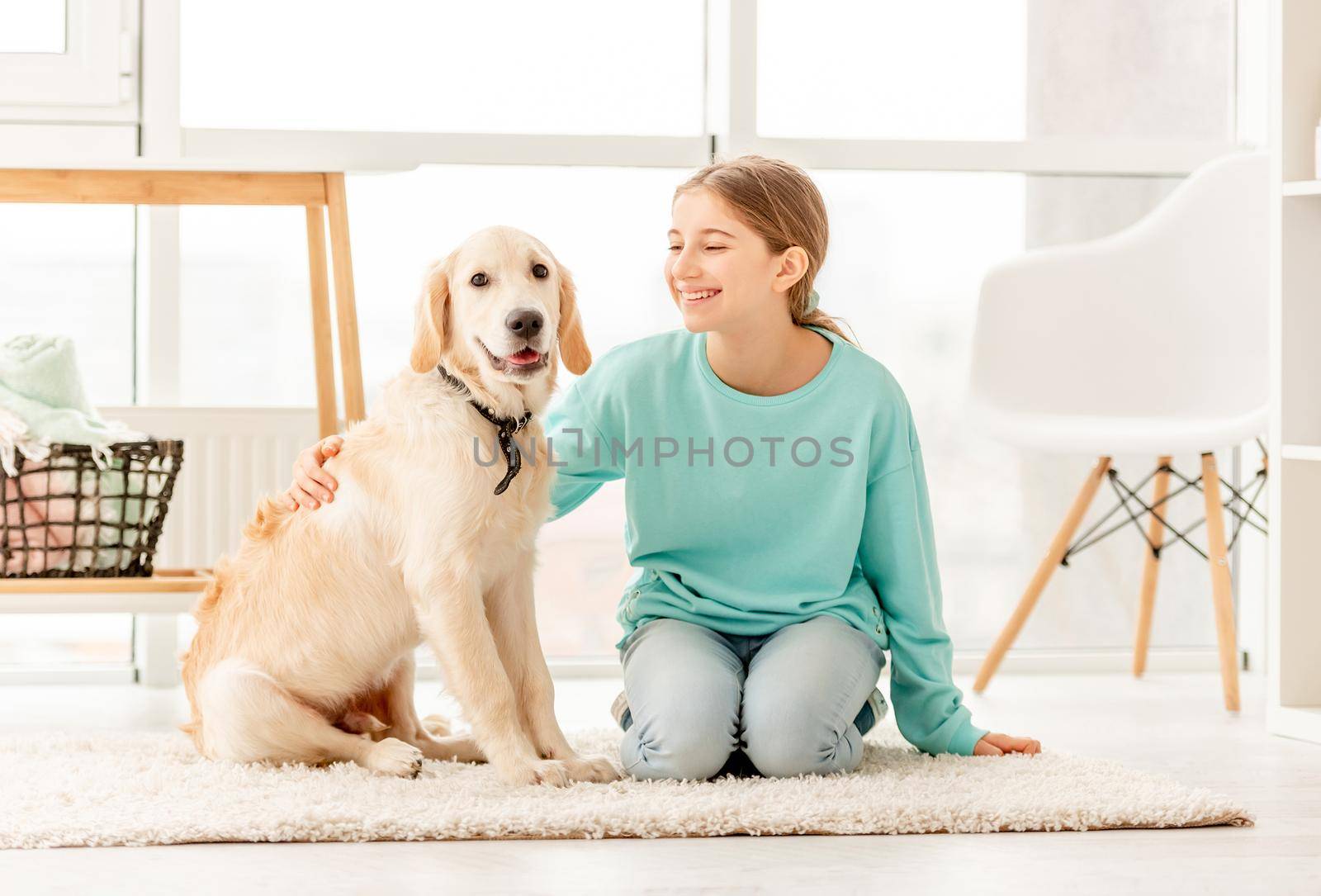 Smiling girl with lovely young dog sitting on floor in light room