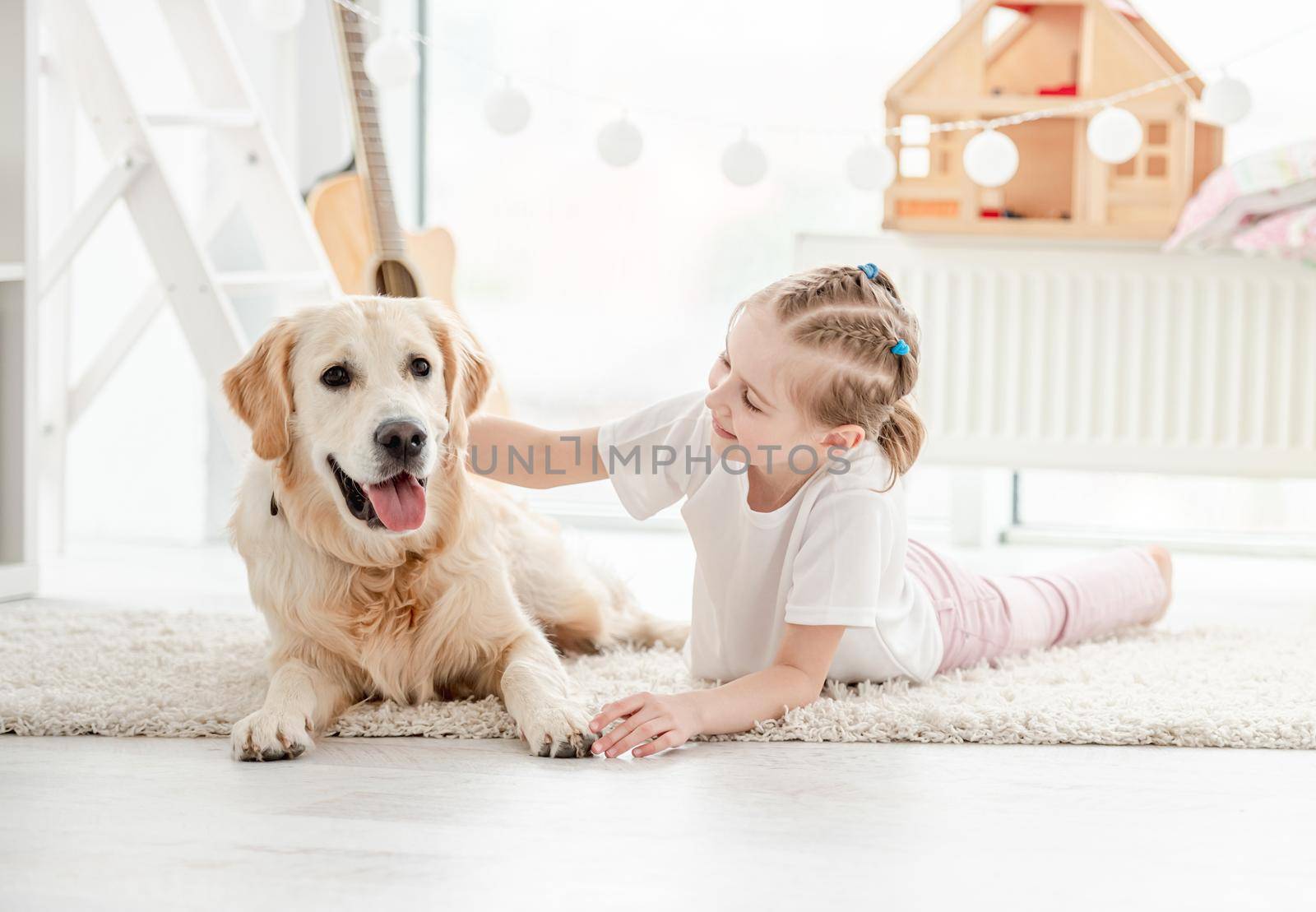 Smiling little girl petting adorable dog in bright room