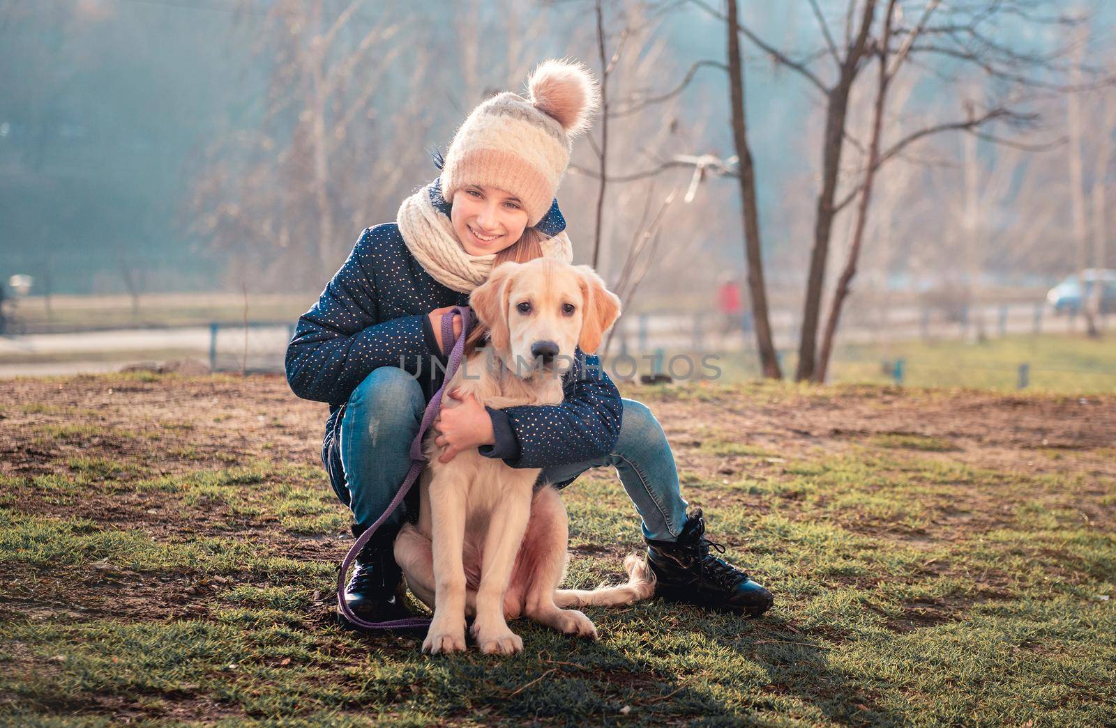 Smiling teenage girl with golden retriever dog in park