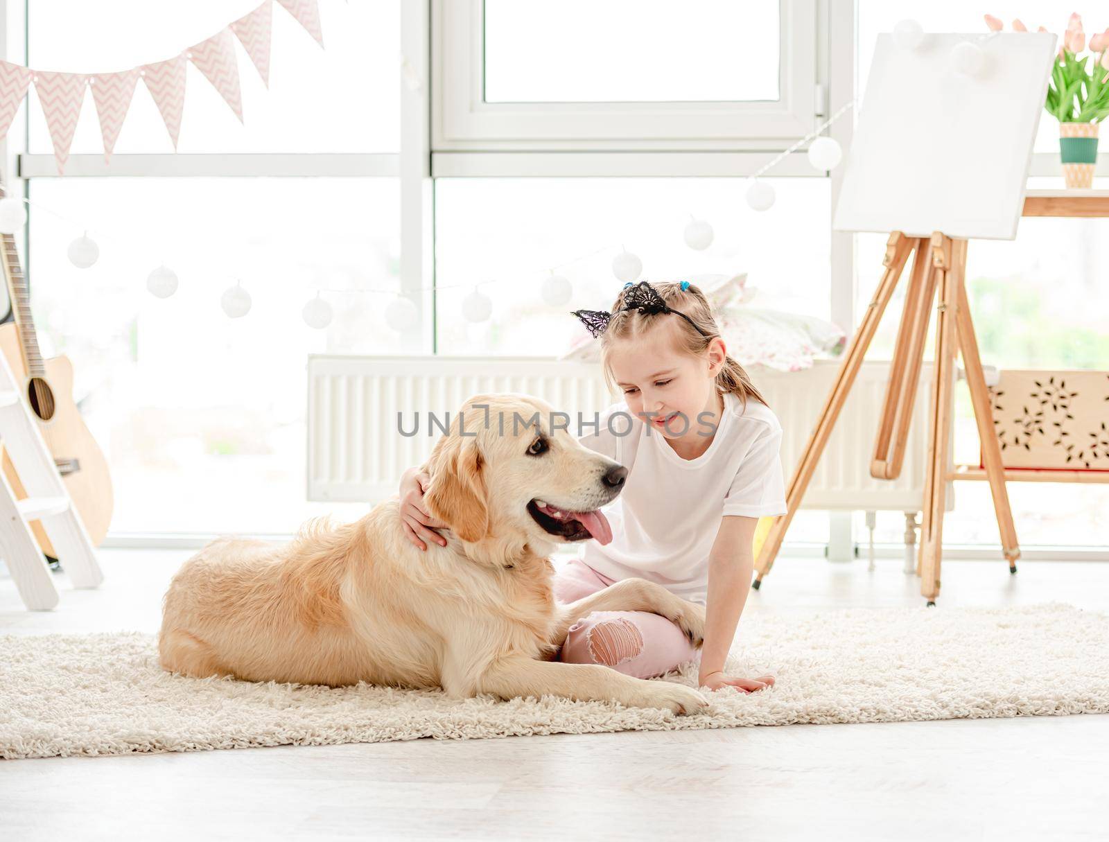 Cute little girl resting with lovely dog in modern apartment