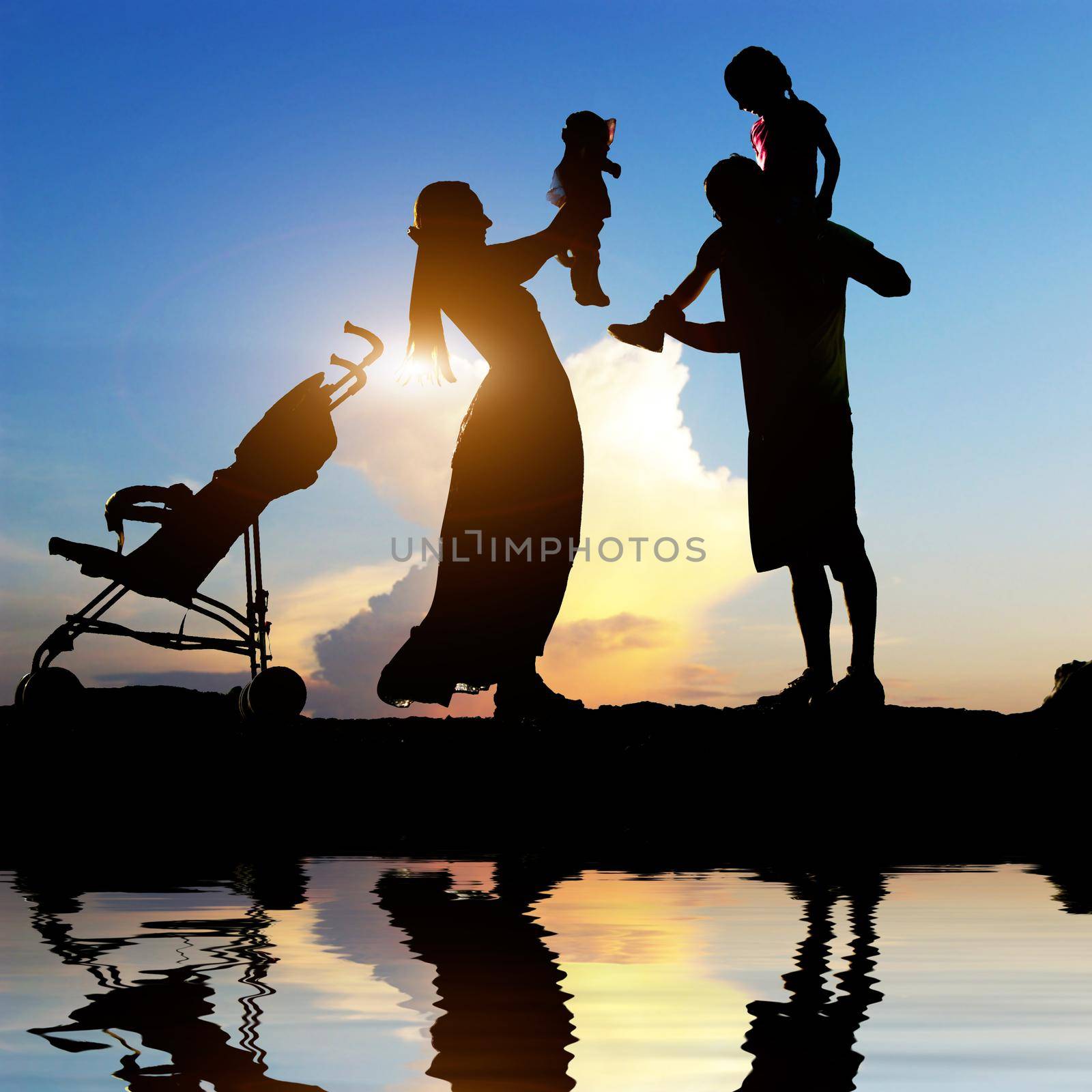 Silhouettes of happy parents having good time with their little children on the seacoast