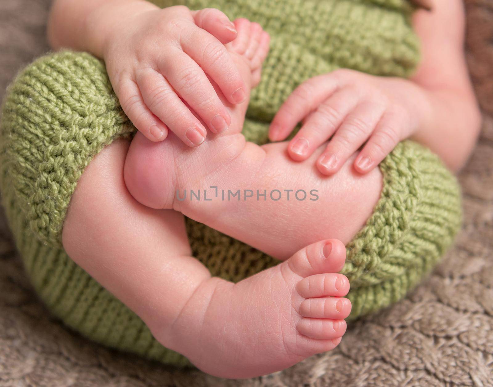 Baby holding his small legs tight in his sleep, closeup