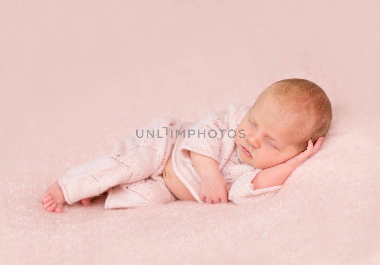 cute sleeping newborn in panties and headband on his head on pink blanket