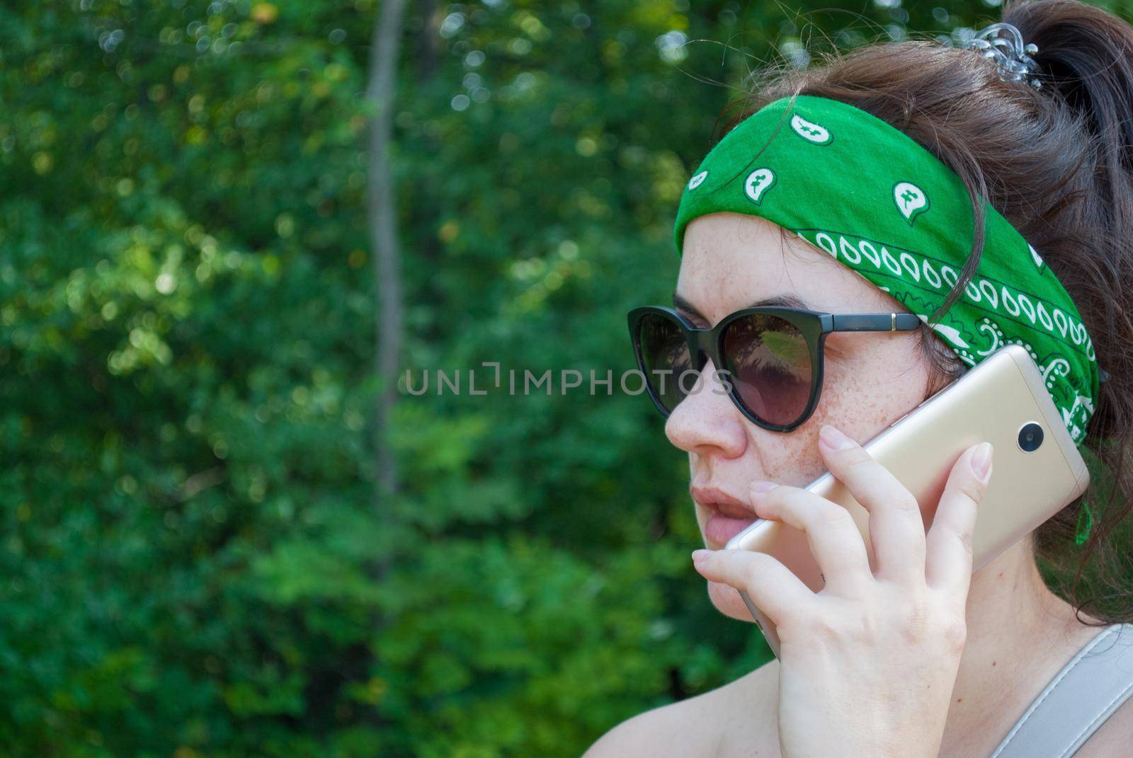 Serious stressed girl speaking on cellphone in park. Frowning young woman in casual calling on mobile phone, listening and staring into distance. Serious phone talk concept.