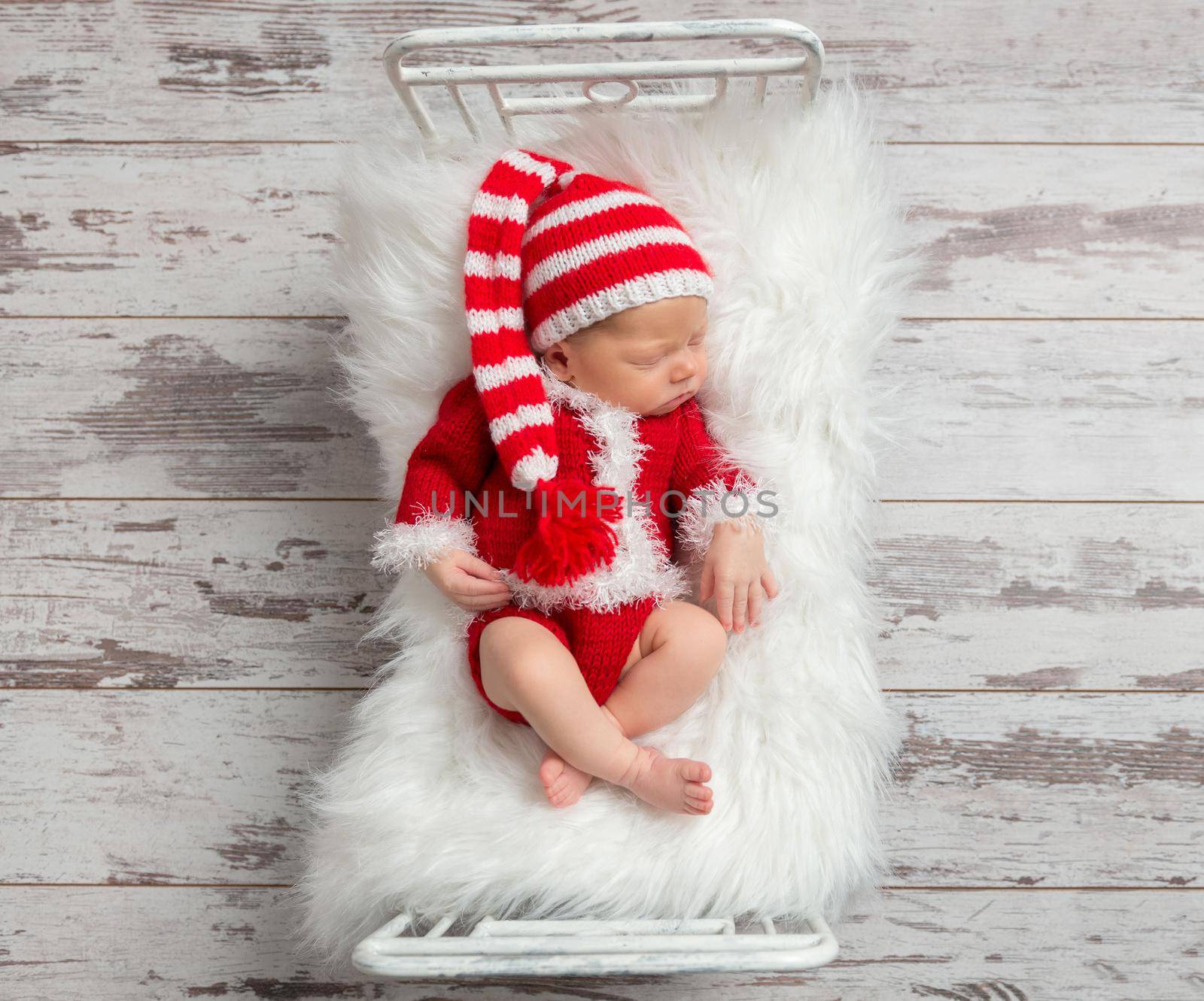 Cute kid in a Christmas costume sleeping in a small bed, topview
