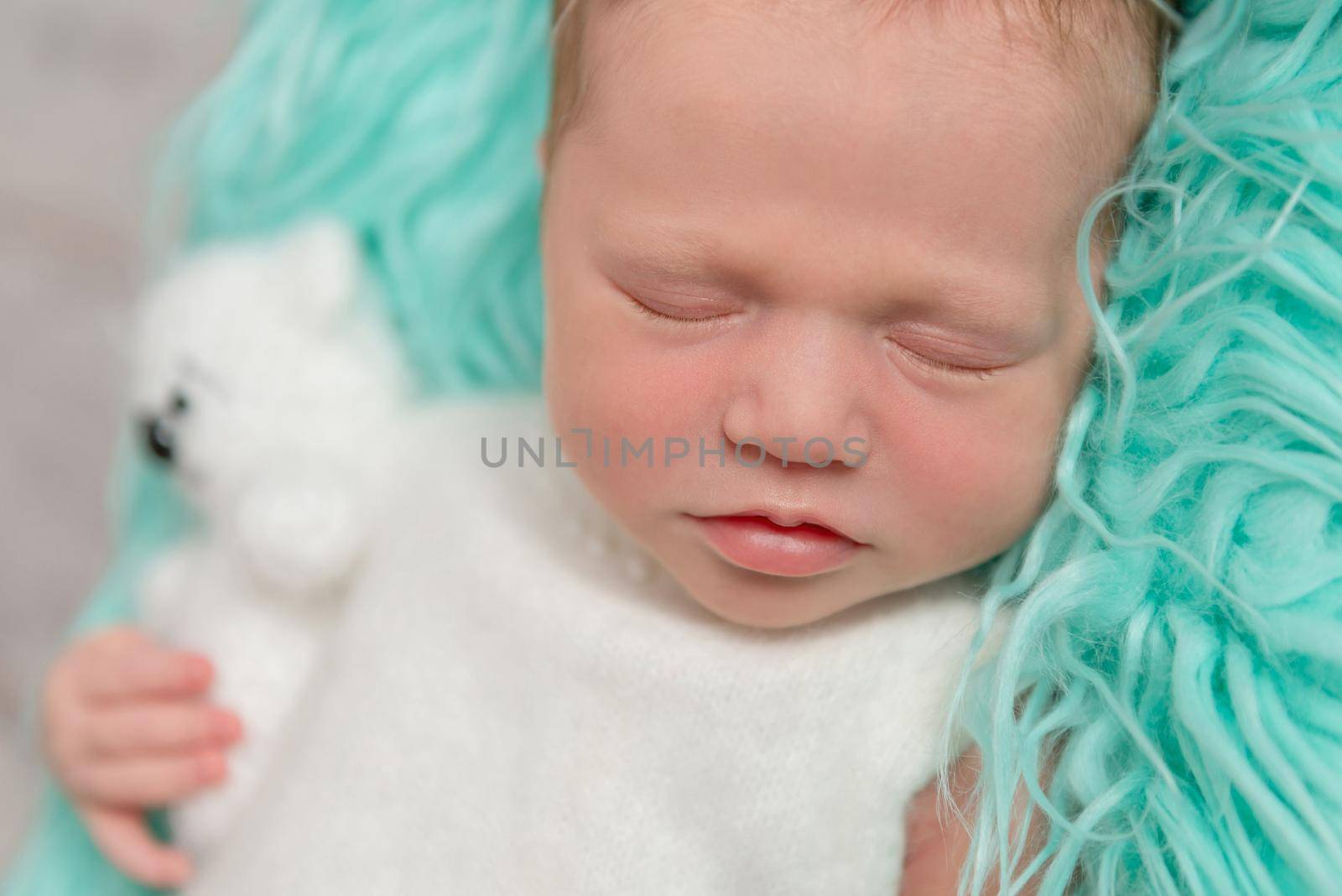 sweet sleeping newborn baby with toy on turquoise fluffy blanket, closeup